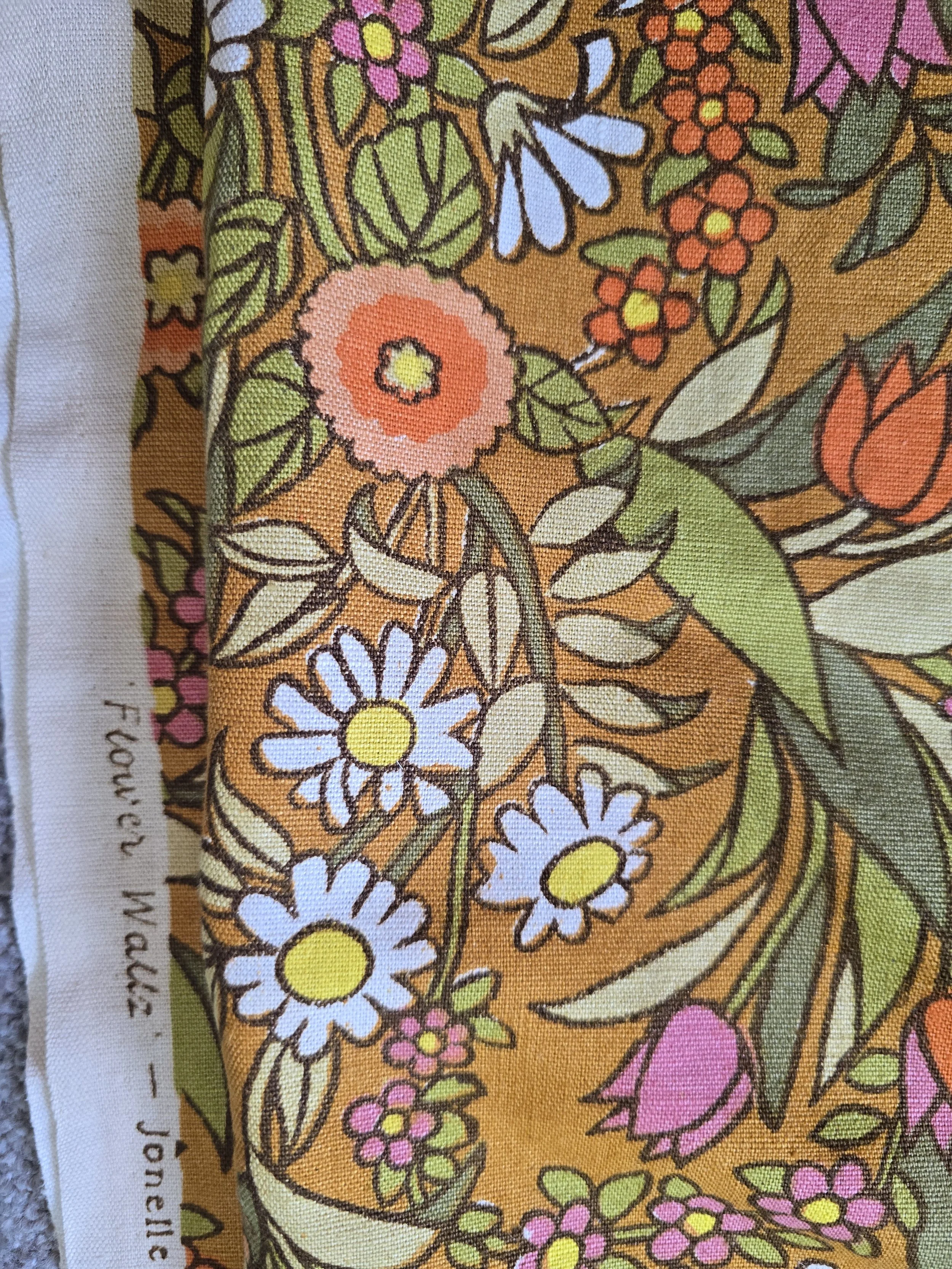 Retro floral textile in shades of ochre, pink, orange, white and green.