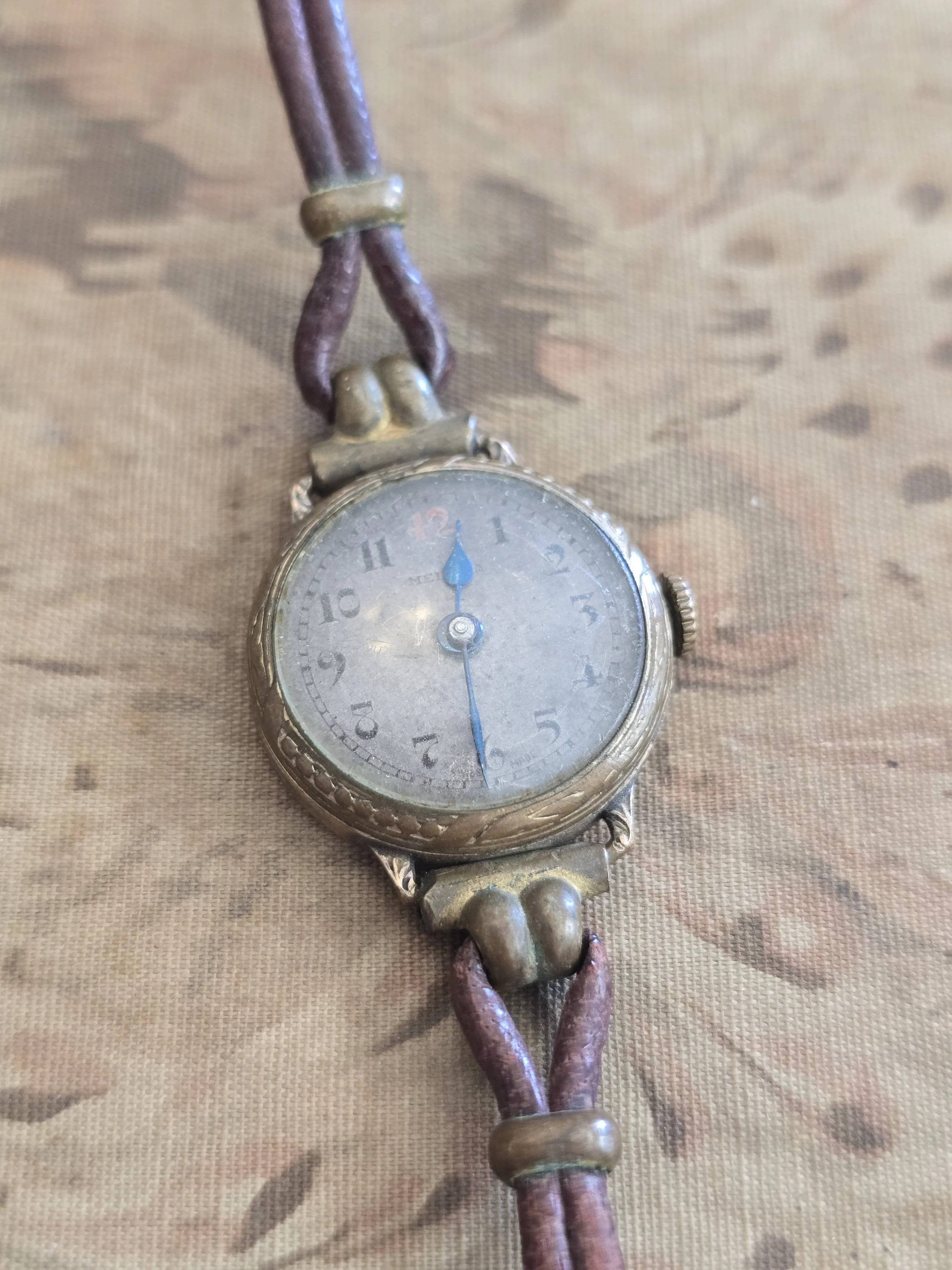 Vintage ladies wristwatch with blue hands and aged silver dial on original cord strap.