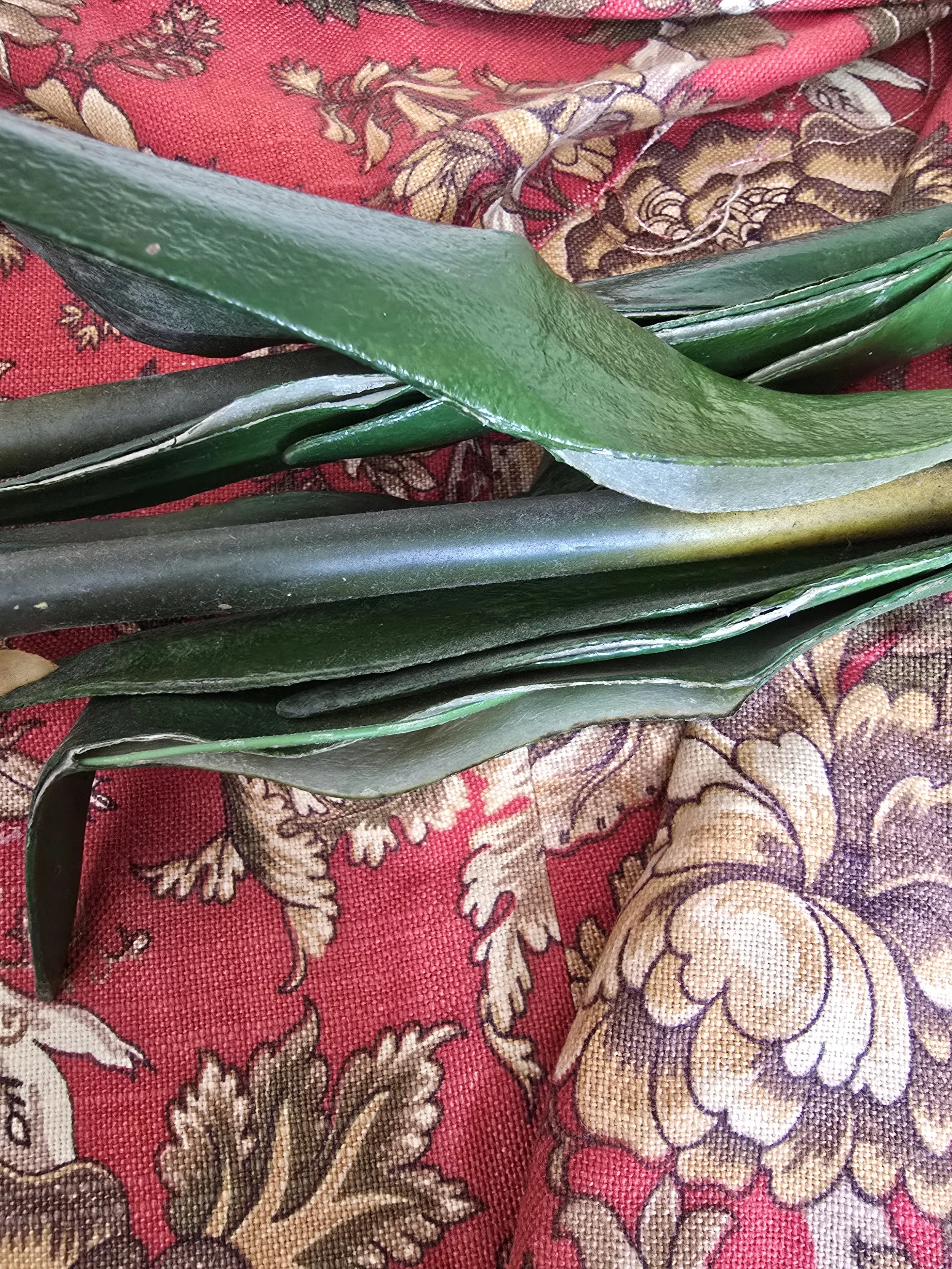 Detailed view of deep red vintage faux amaryllis petals with green stems and silk leaves.