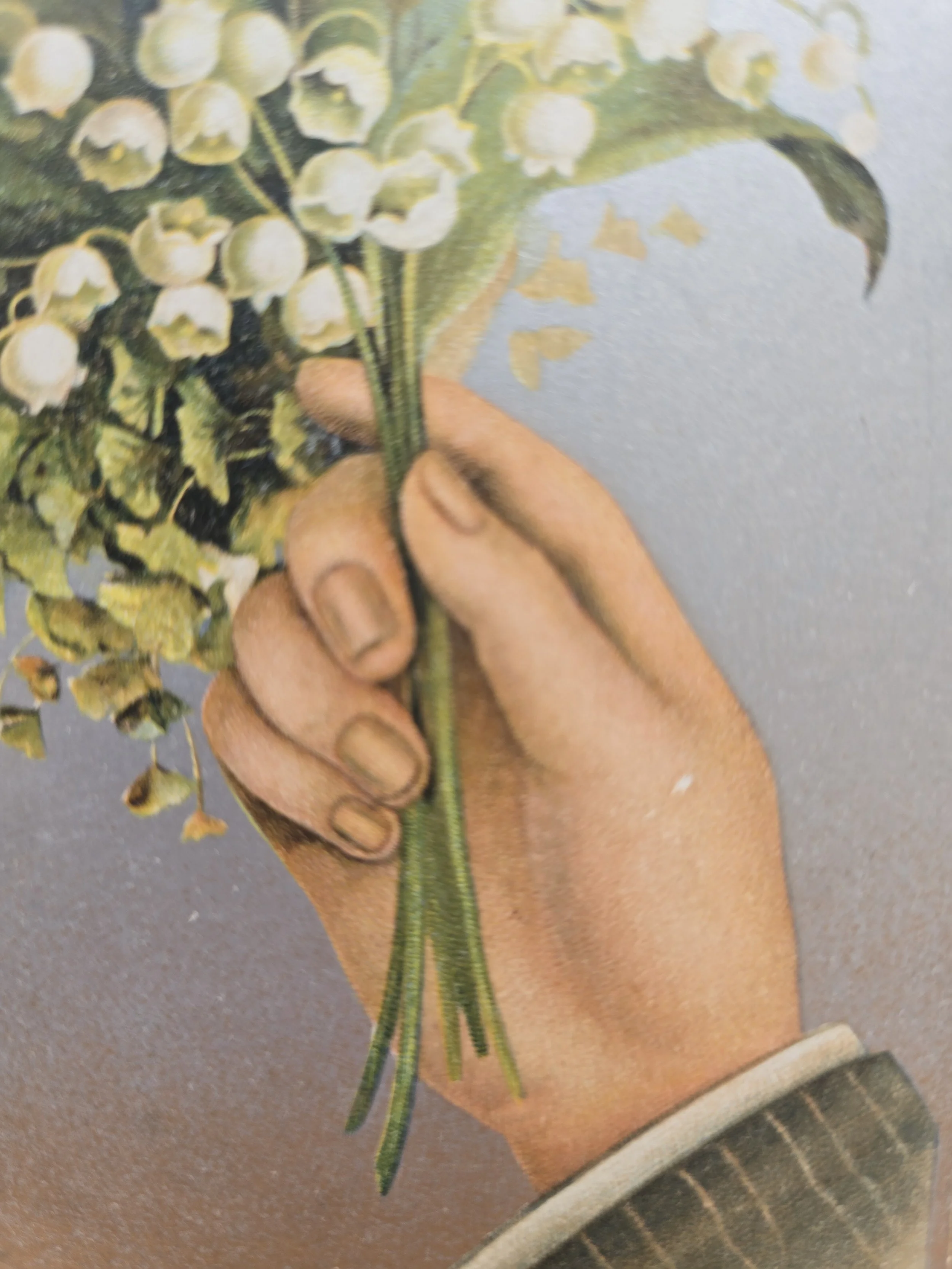 Antique Edwardian postcard showing a hand holding lily of the valley flowers