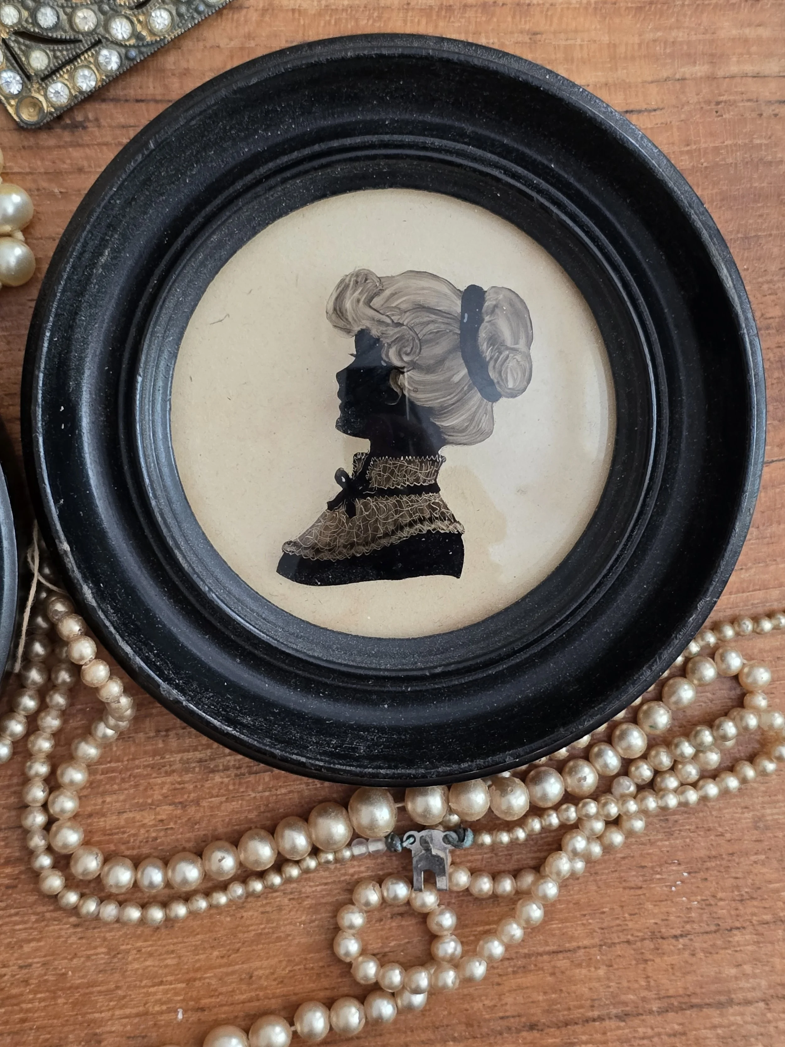 Antique lady silhouette portrait with hand-painted hair and gilt detailing beneath convex glass.