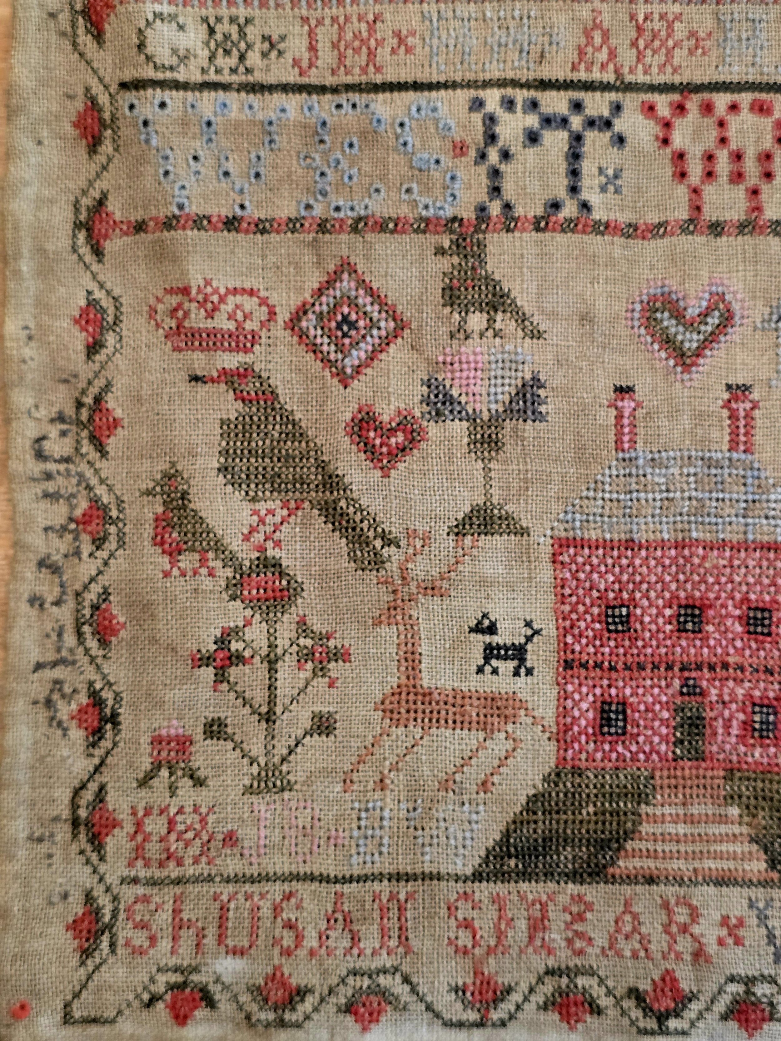 Antique Scottish folk art sampler showing embroidered birds, deer, flowers and decorative borders on aged linen.