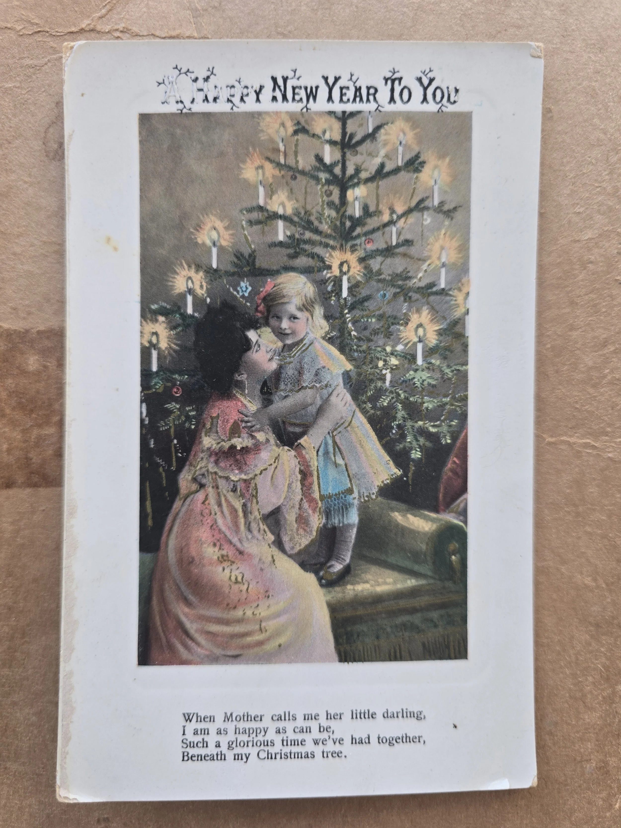 Antique Edwardian New Year postcard showing mother and child beside a candlelit Christmas tree