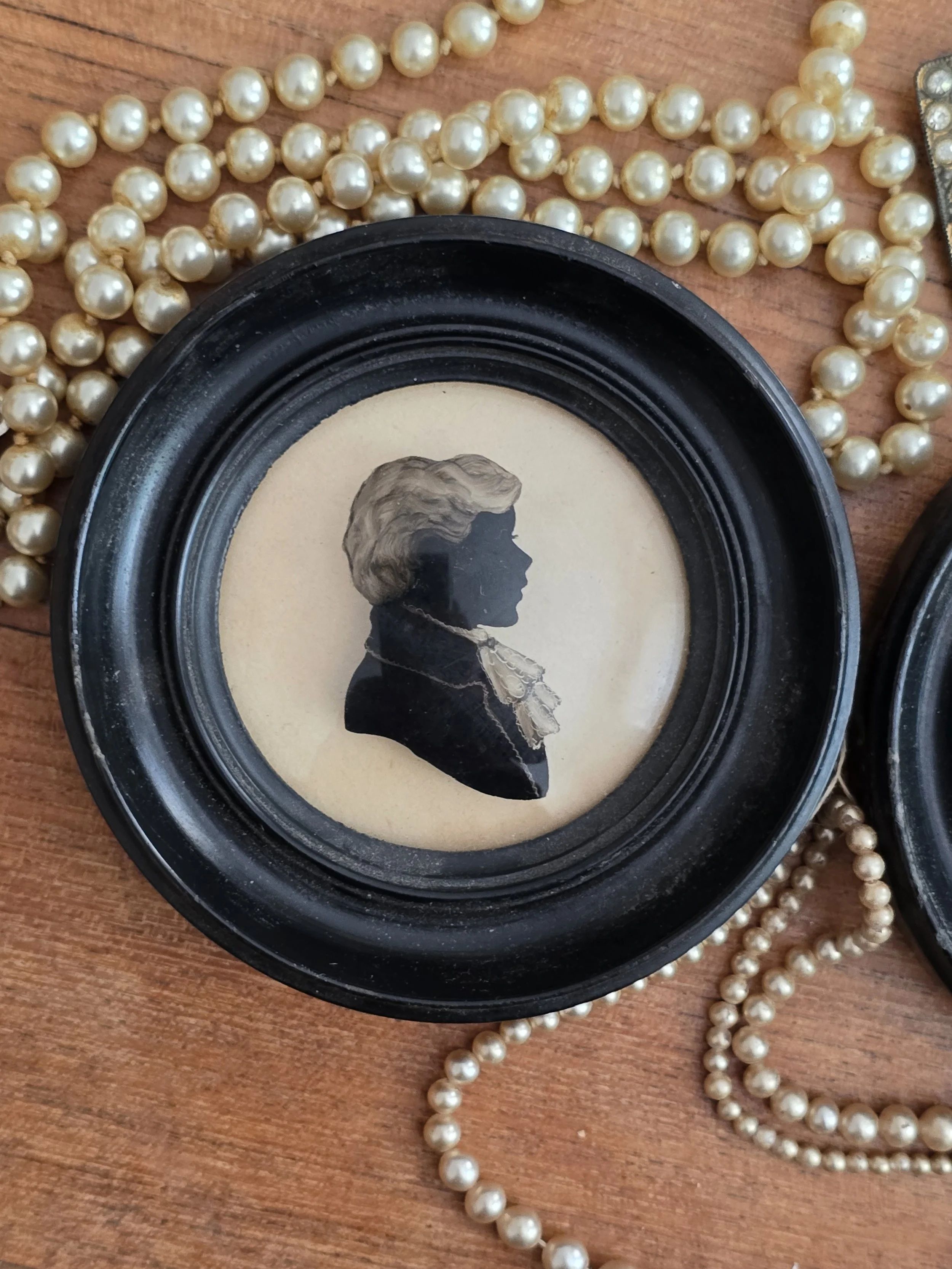 Antique gentleman silhouette portrait beneath convex glass in an ebonised frame.