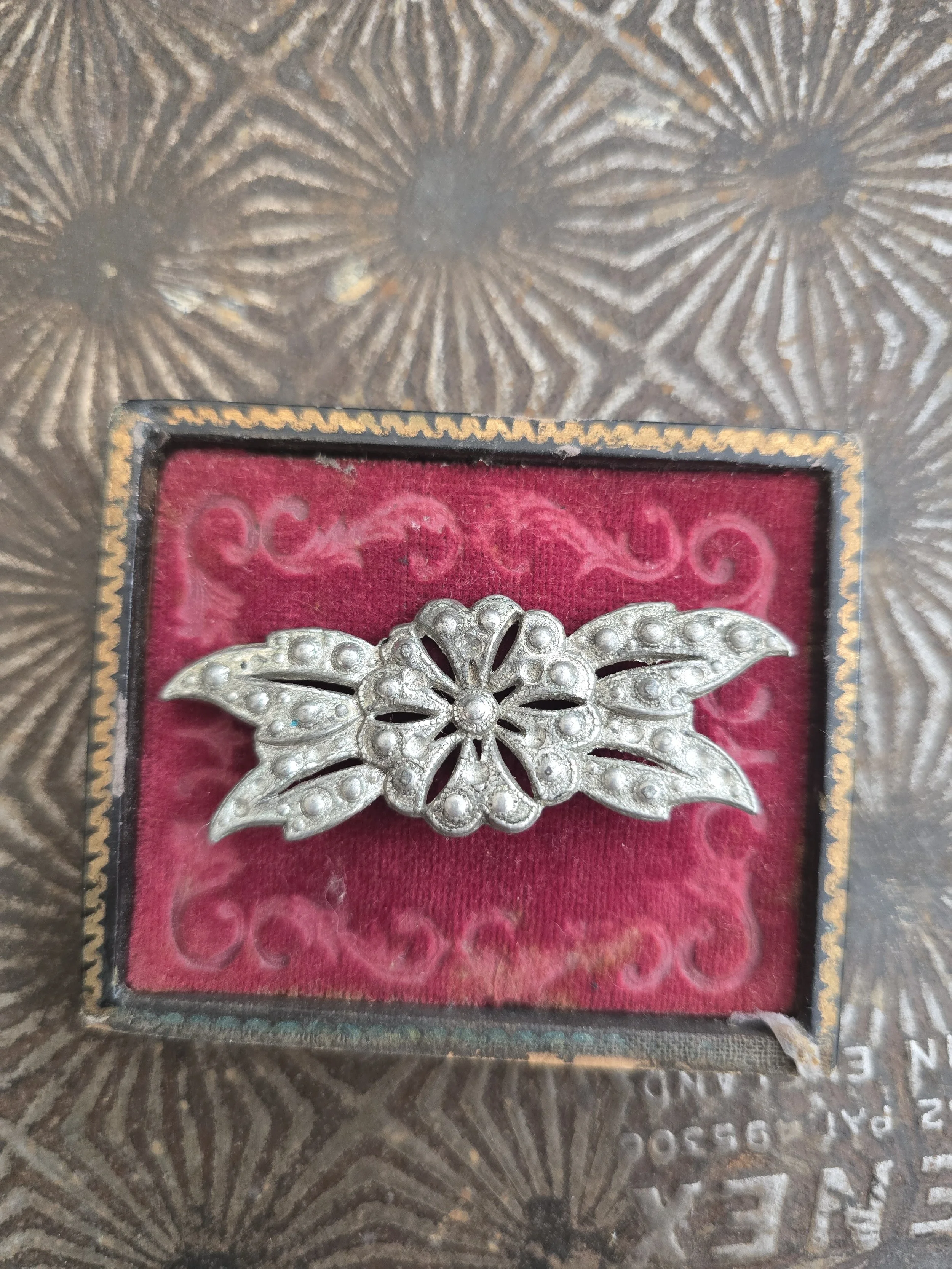 Vintage silver-tone floral brooch with openwork leaf design displayed on a burgundy velvet presentation box.