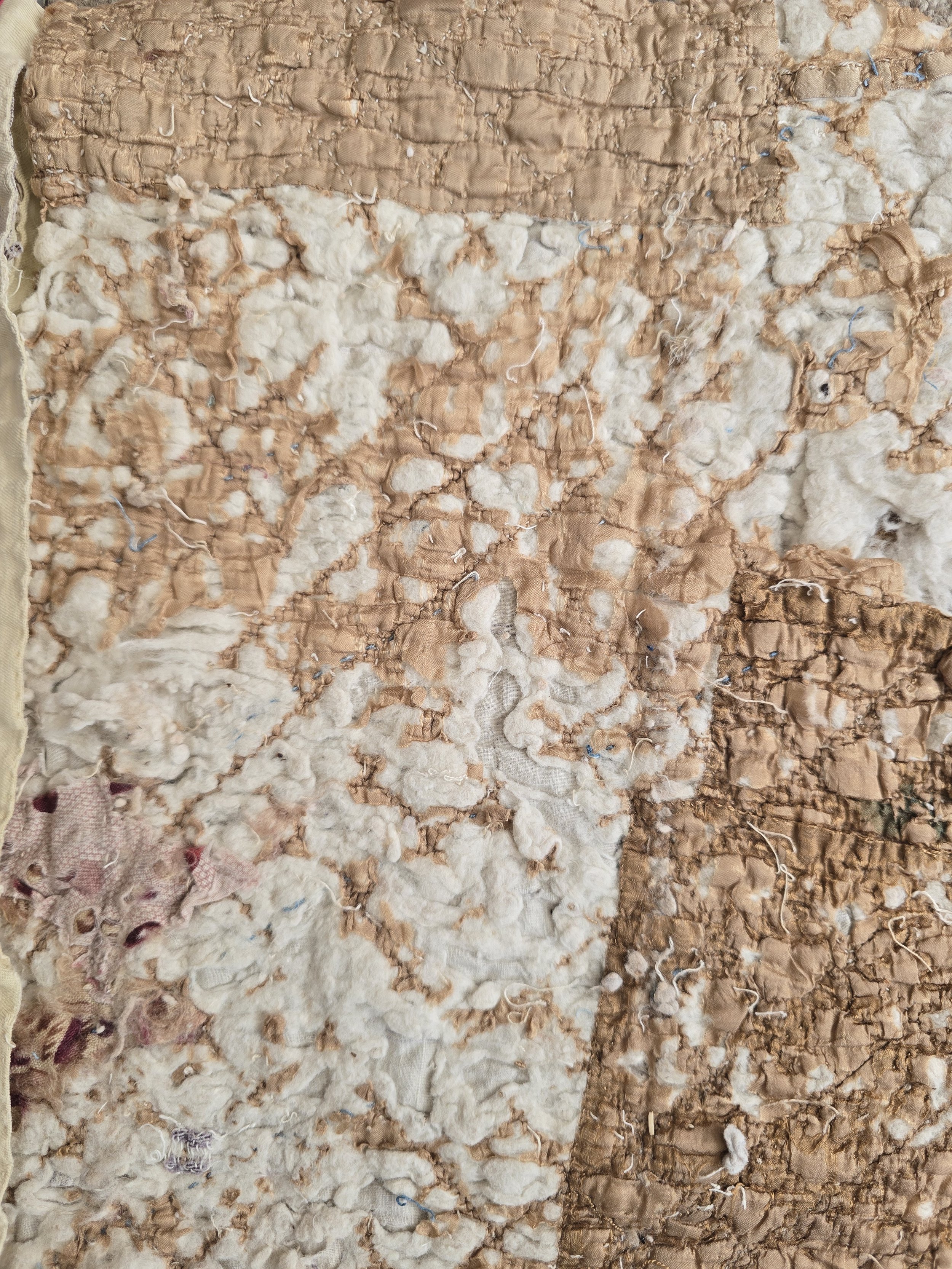 Antique French quilt fragment with faded purple printed cotton and exposed layers.