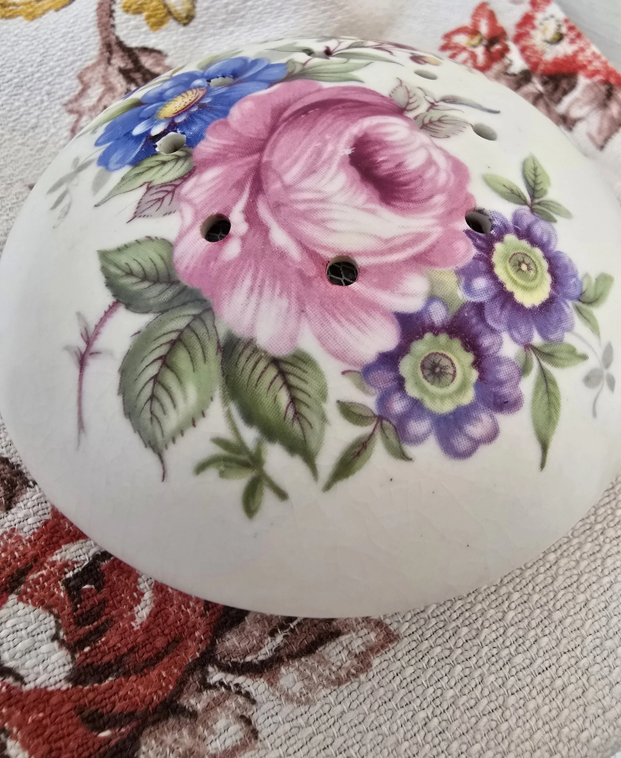 Lavender-filled ceramic pomander shown on a floral textile background