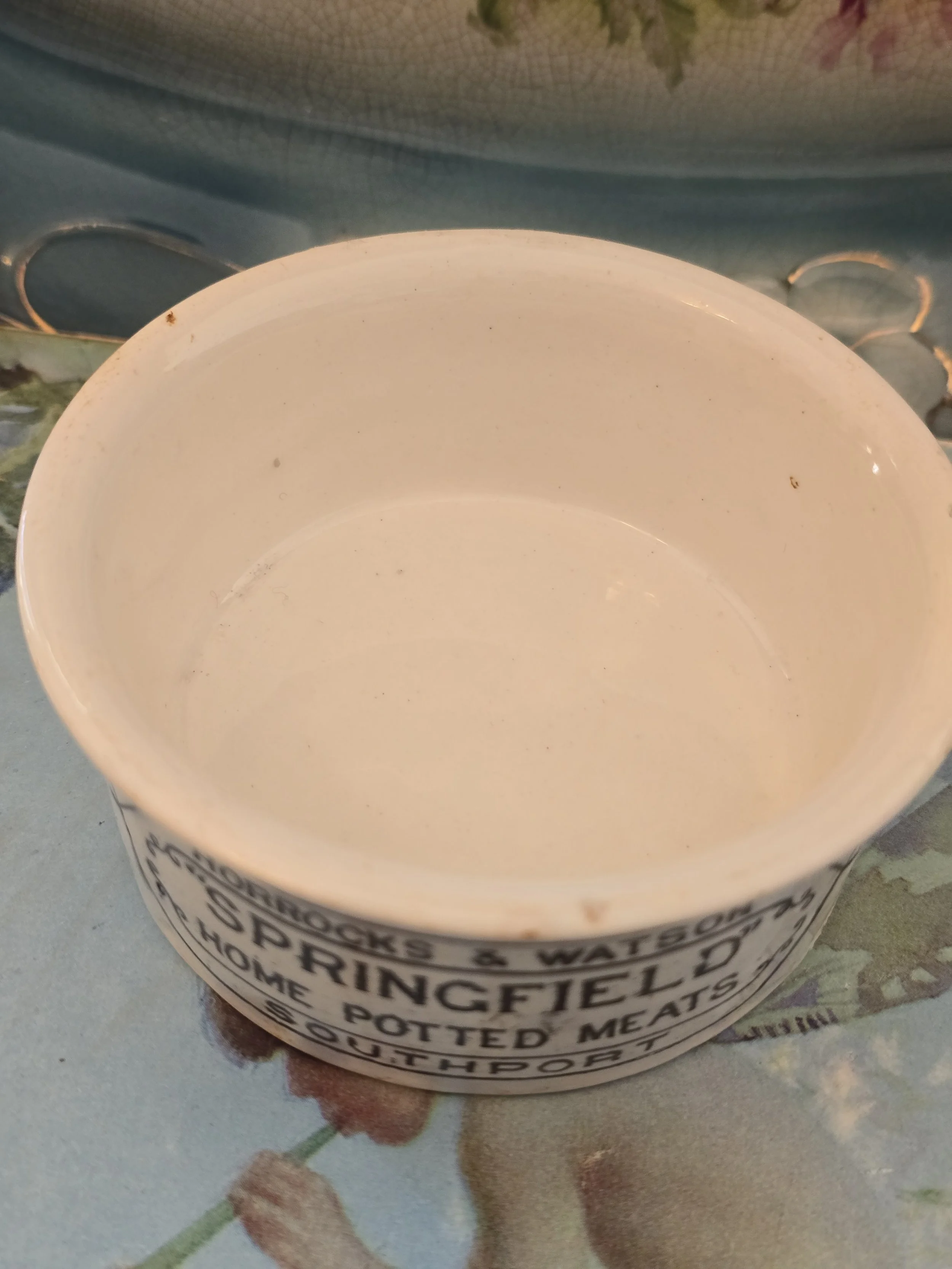 Side view of antique cream glazed potted meat container showing its gently flared rim.