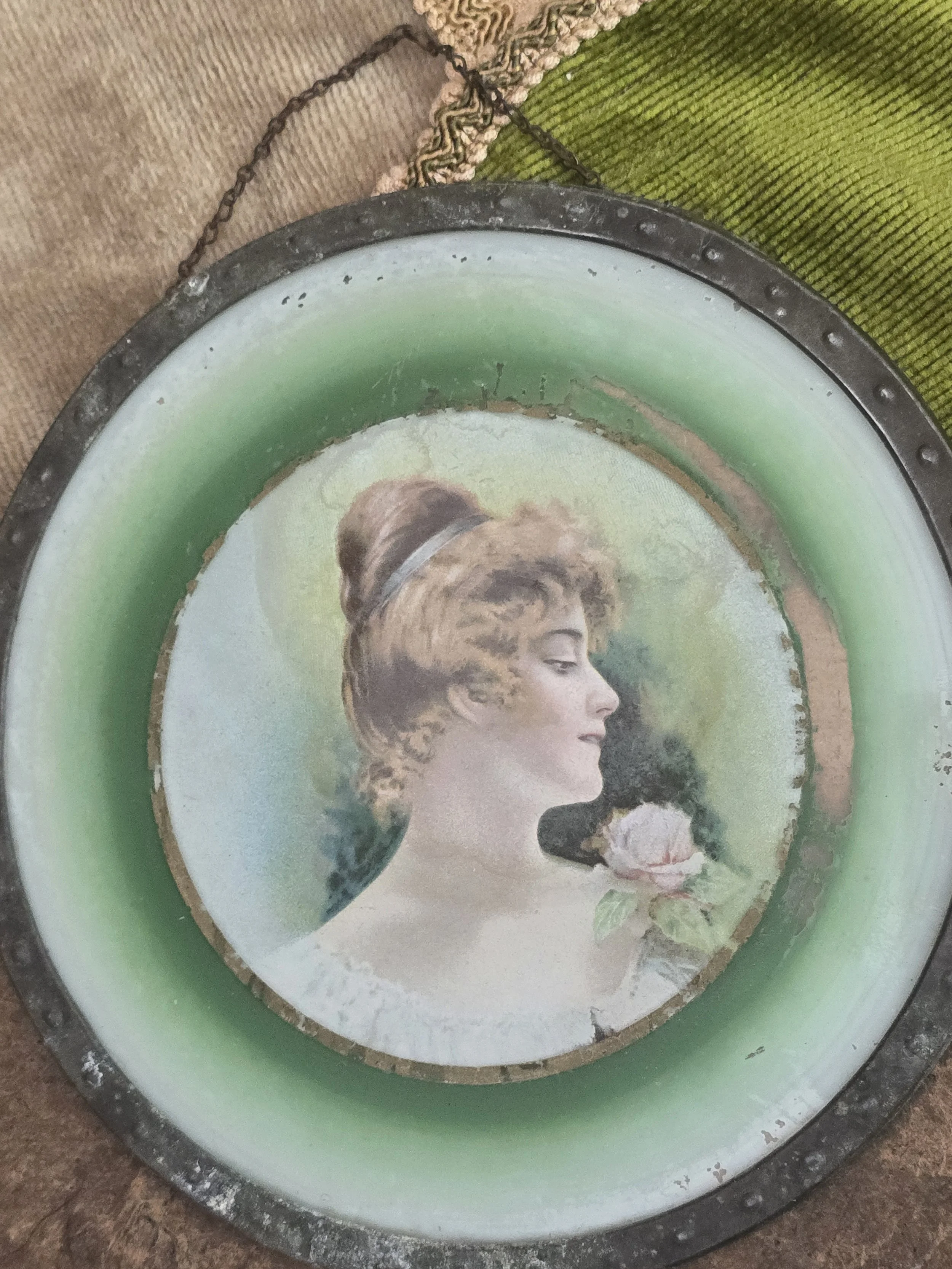 Antique portrait plaque of a young woman with rose beneath green glass.
