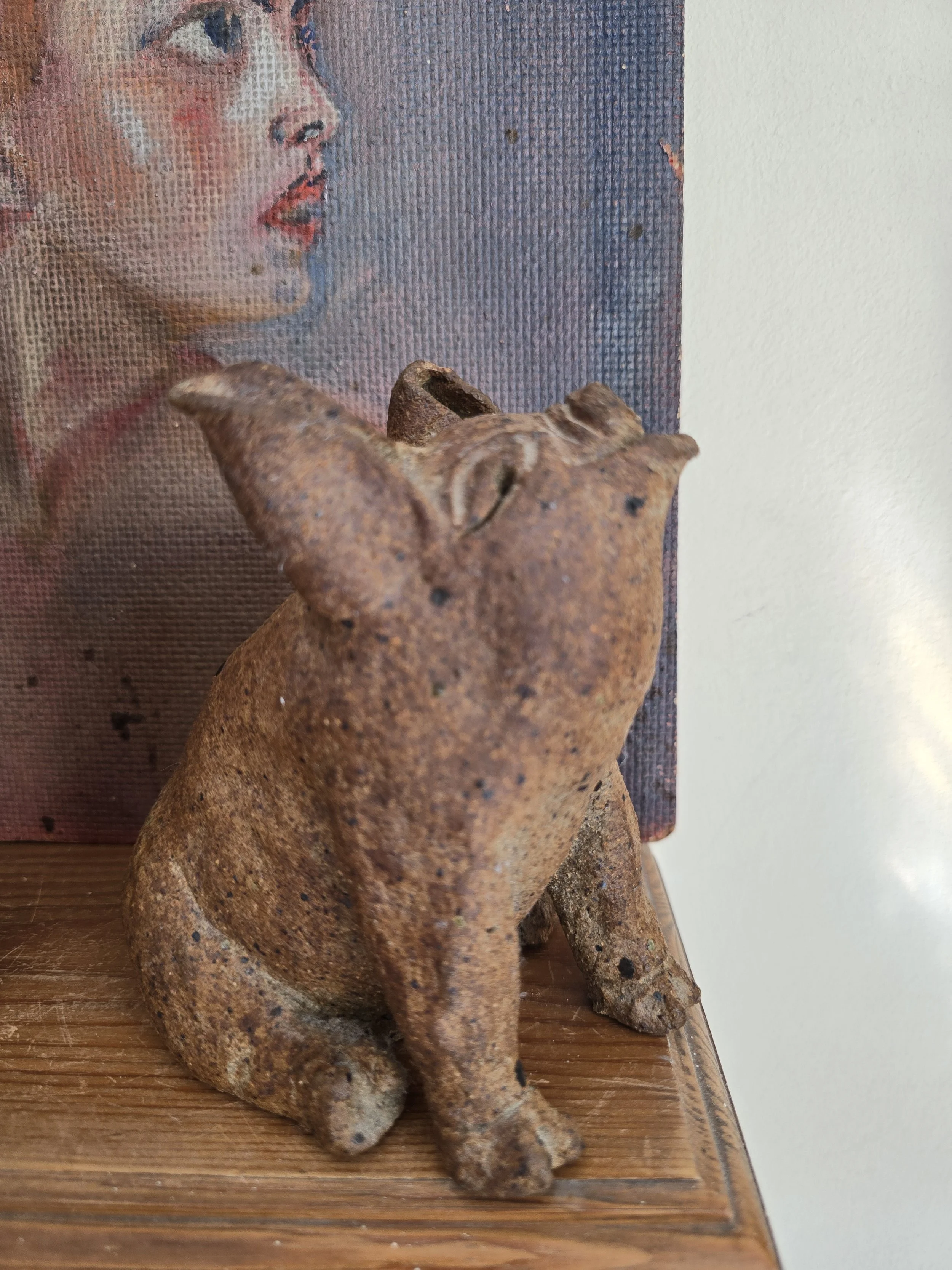 Hand-modelled primitive pottery pig in warm brown heavily speckled clay, approximately 16 cm tall.