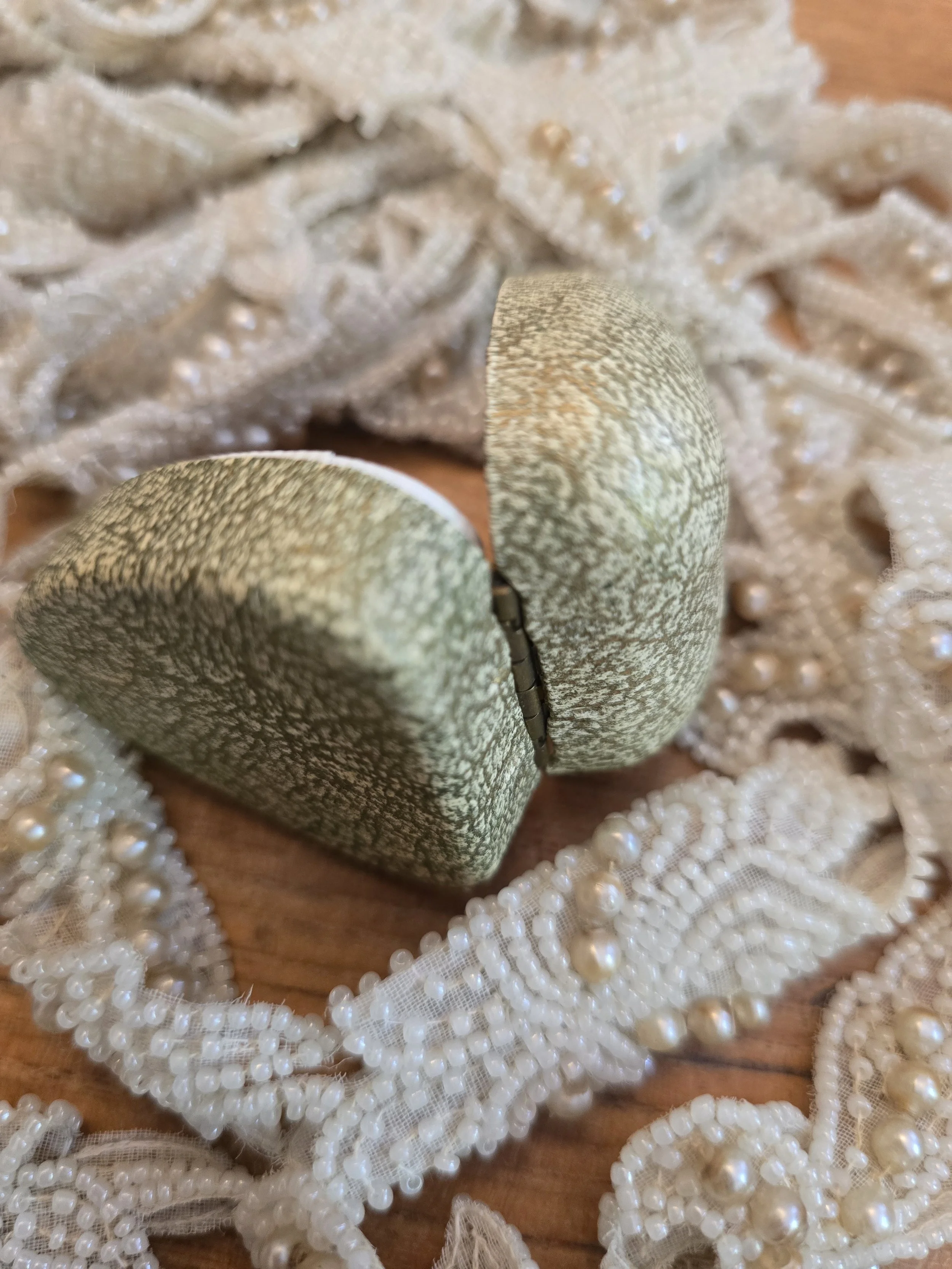 Small vintage ring presentation box with original hinge and textured fabric covering.