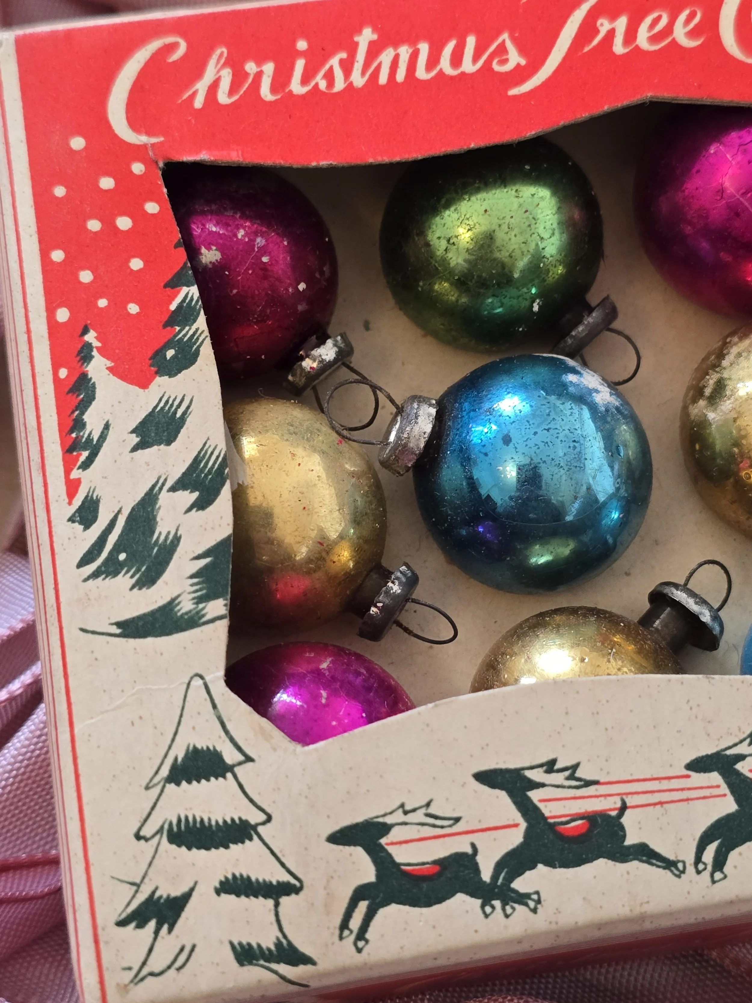 Illustrated red vintage Christmas decoration box showing Father Christmas, reindeer and snowy trees.