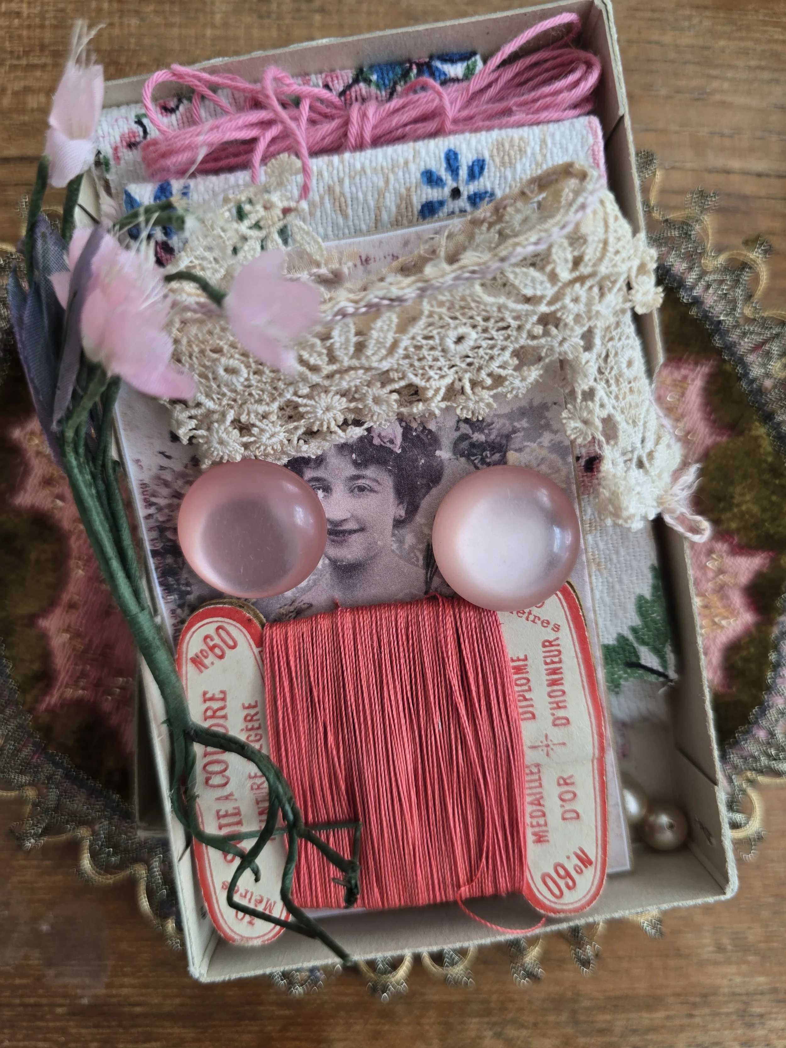 Original French À La Croix sewing box filled with vintage haberdashery including pink thread, lace, floral fabric, millinery flowers, faux pearls and a handmade card with vintage buttons.