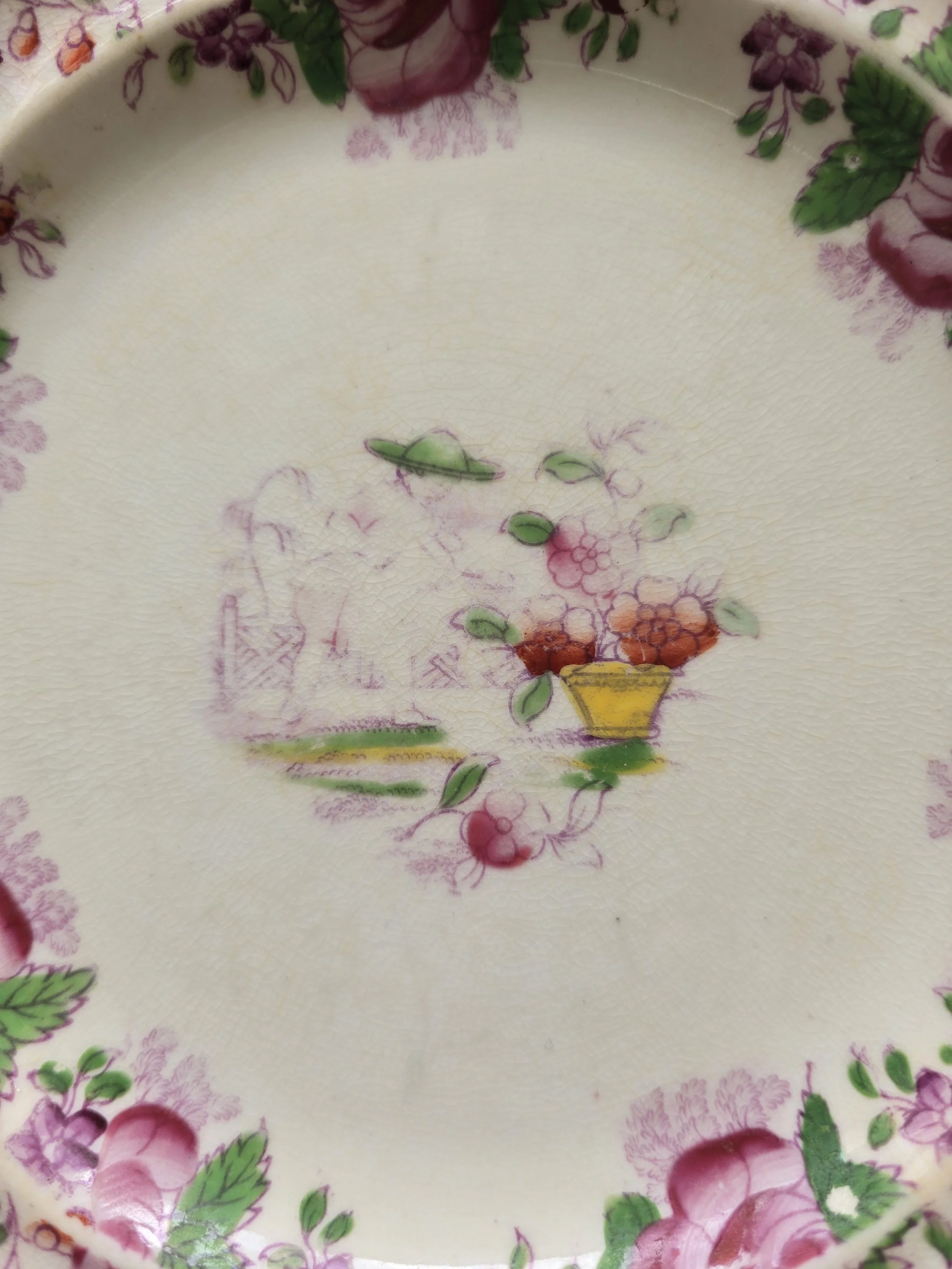 Faded pastoral scene in the centre of an antique transferware plate.