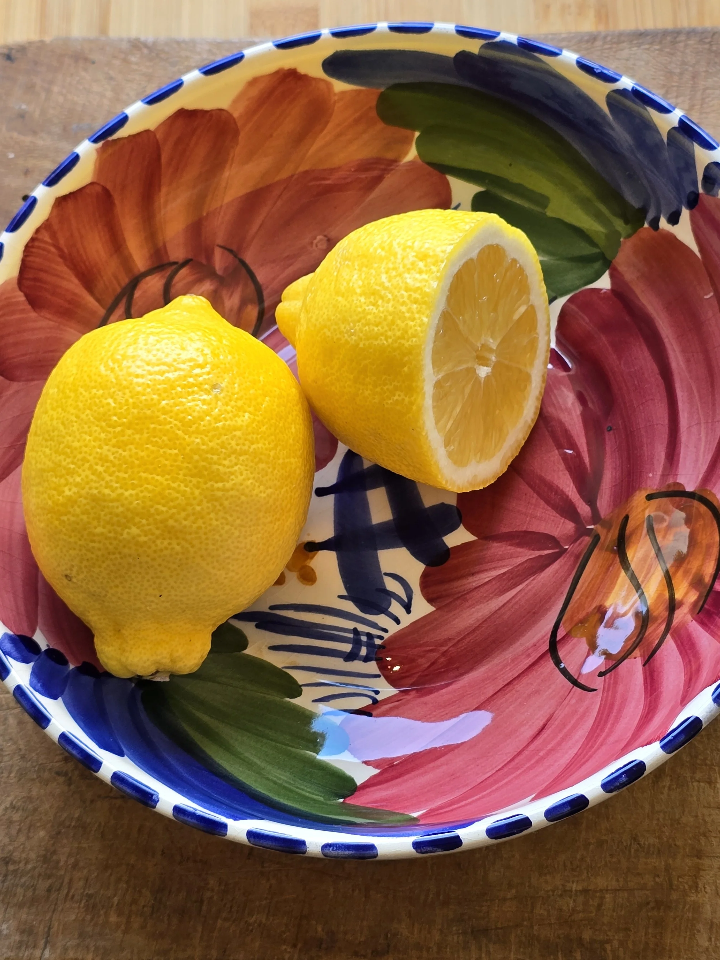 Hand-painted ceramic bowl with bold floral design, styled with fresh lemons