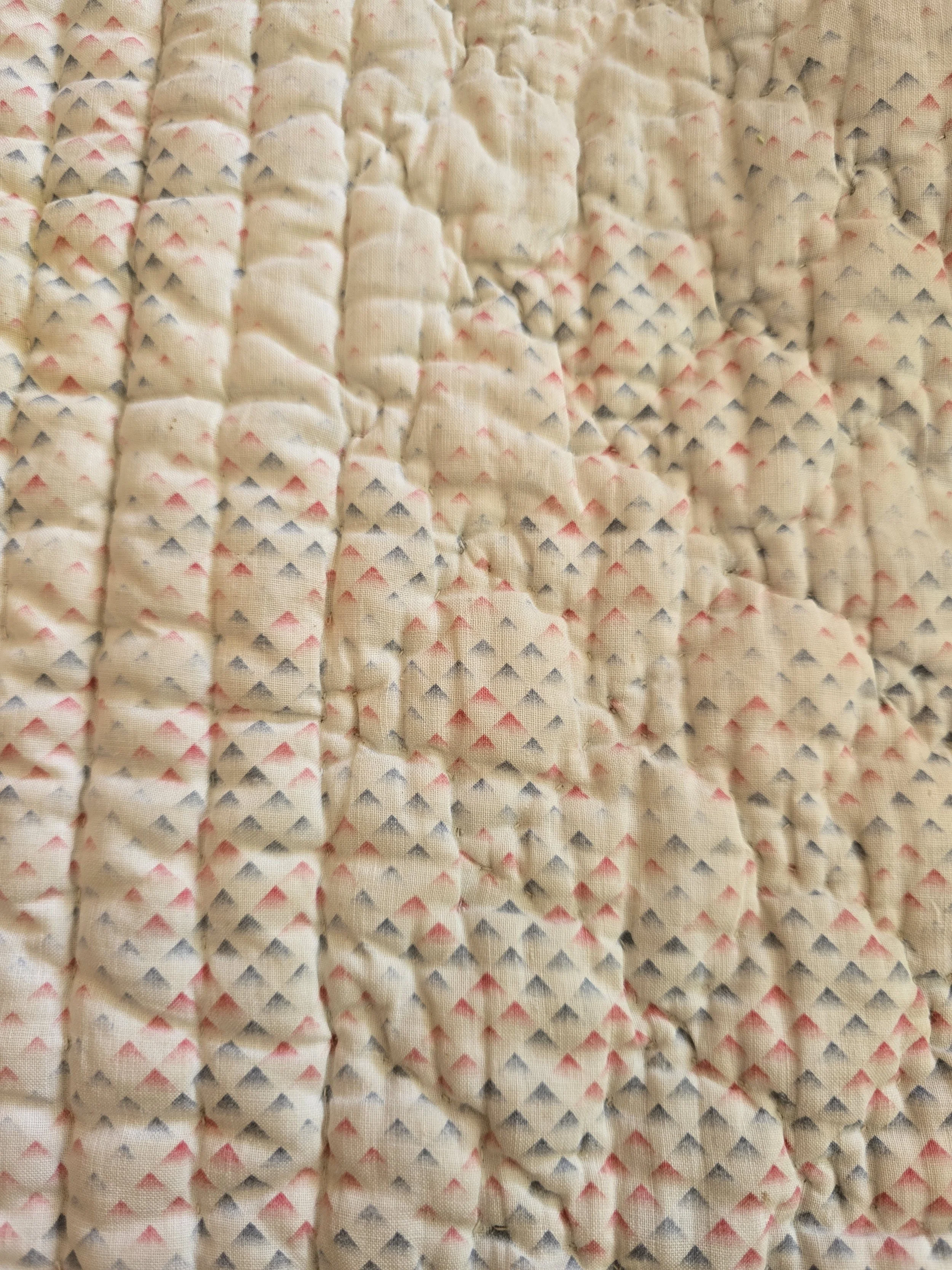 Reverse of French quilted cotton textile showing geometric pink and blue pattern.