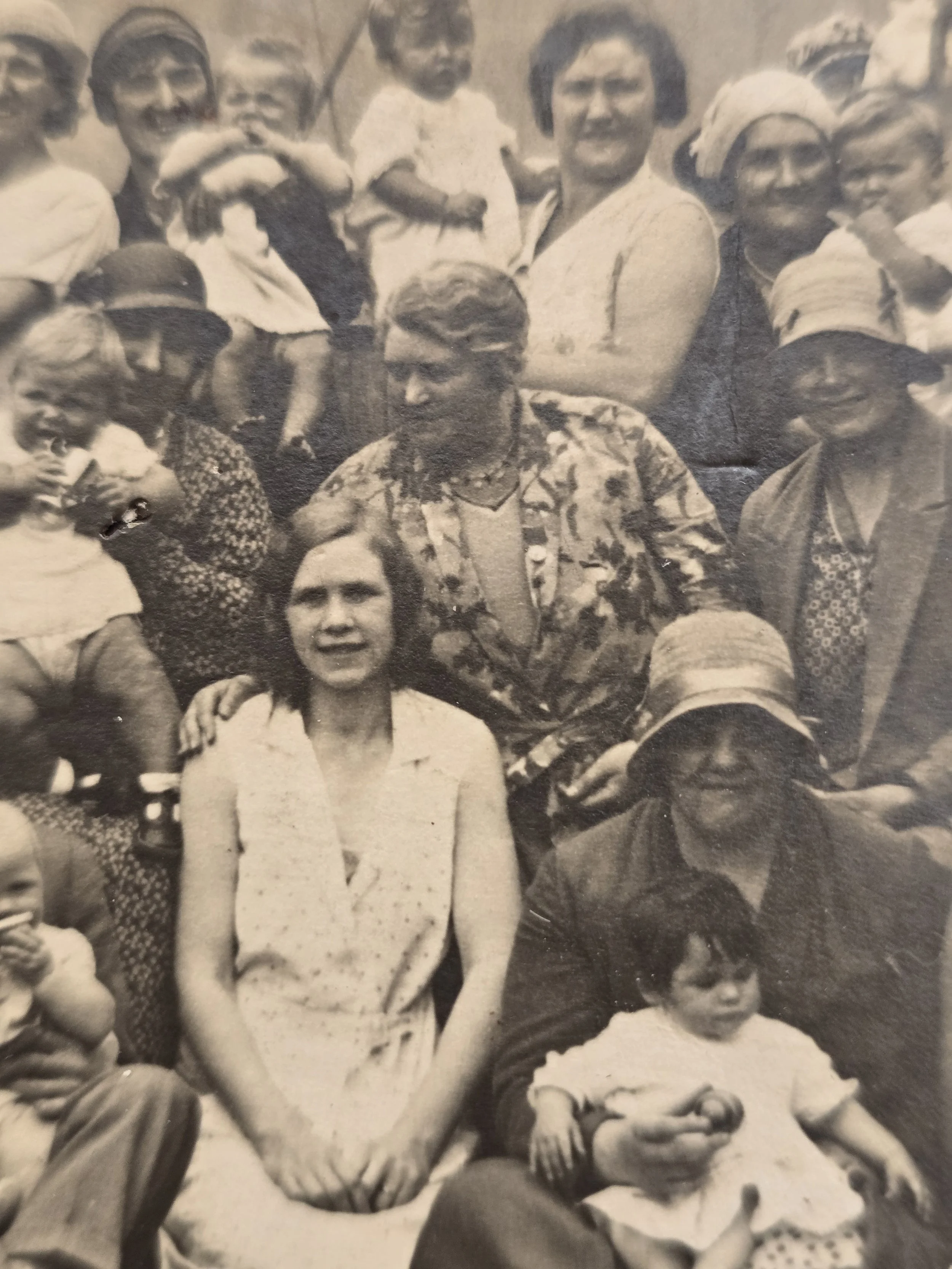Close-up of 1930s group photograph showing women, children and a seated man holding two babies.
