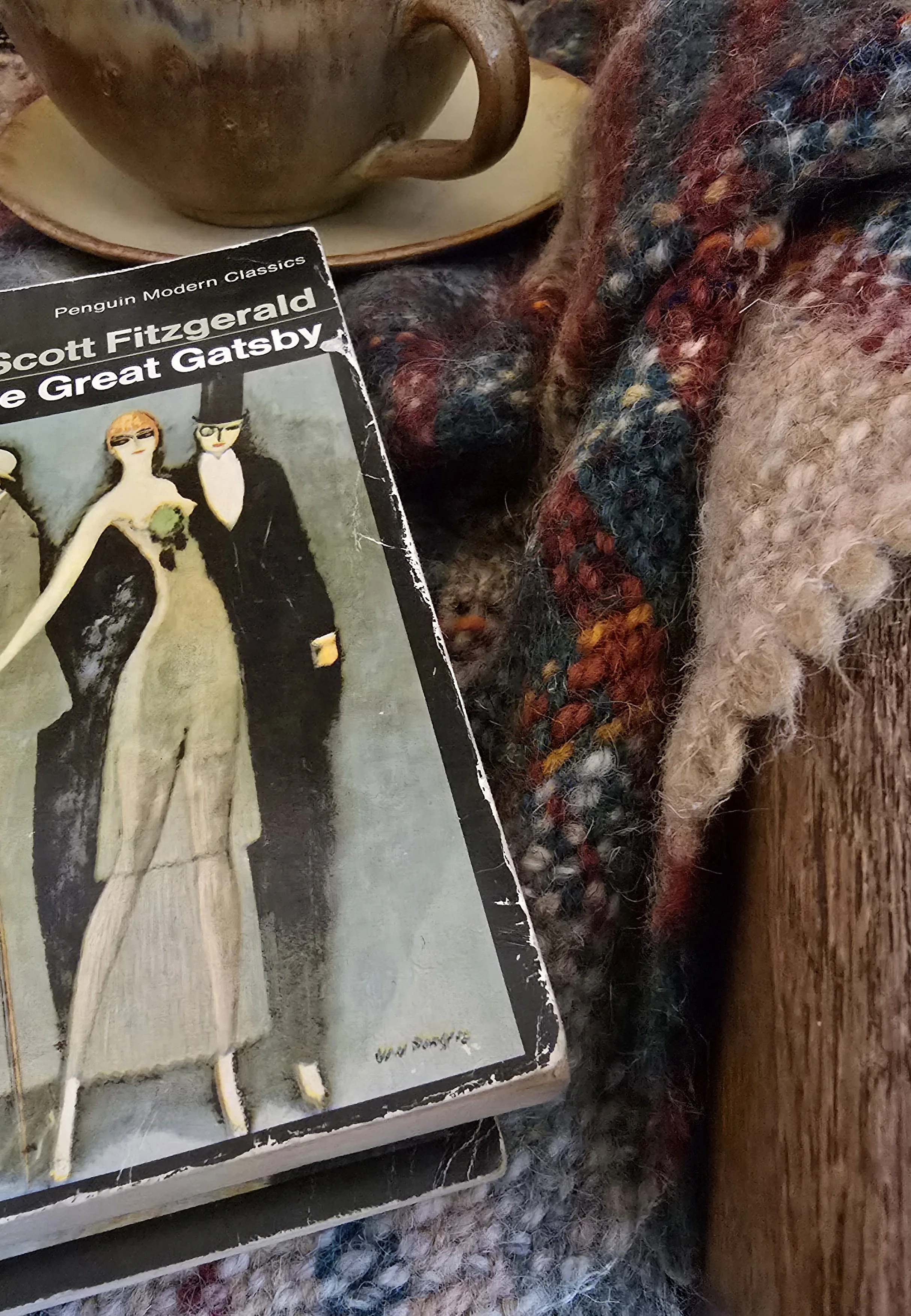 Styled shot of The Great Gatsby Penguin edition beside a mug and wool blanket.