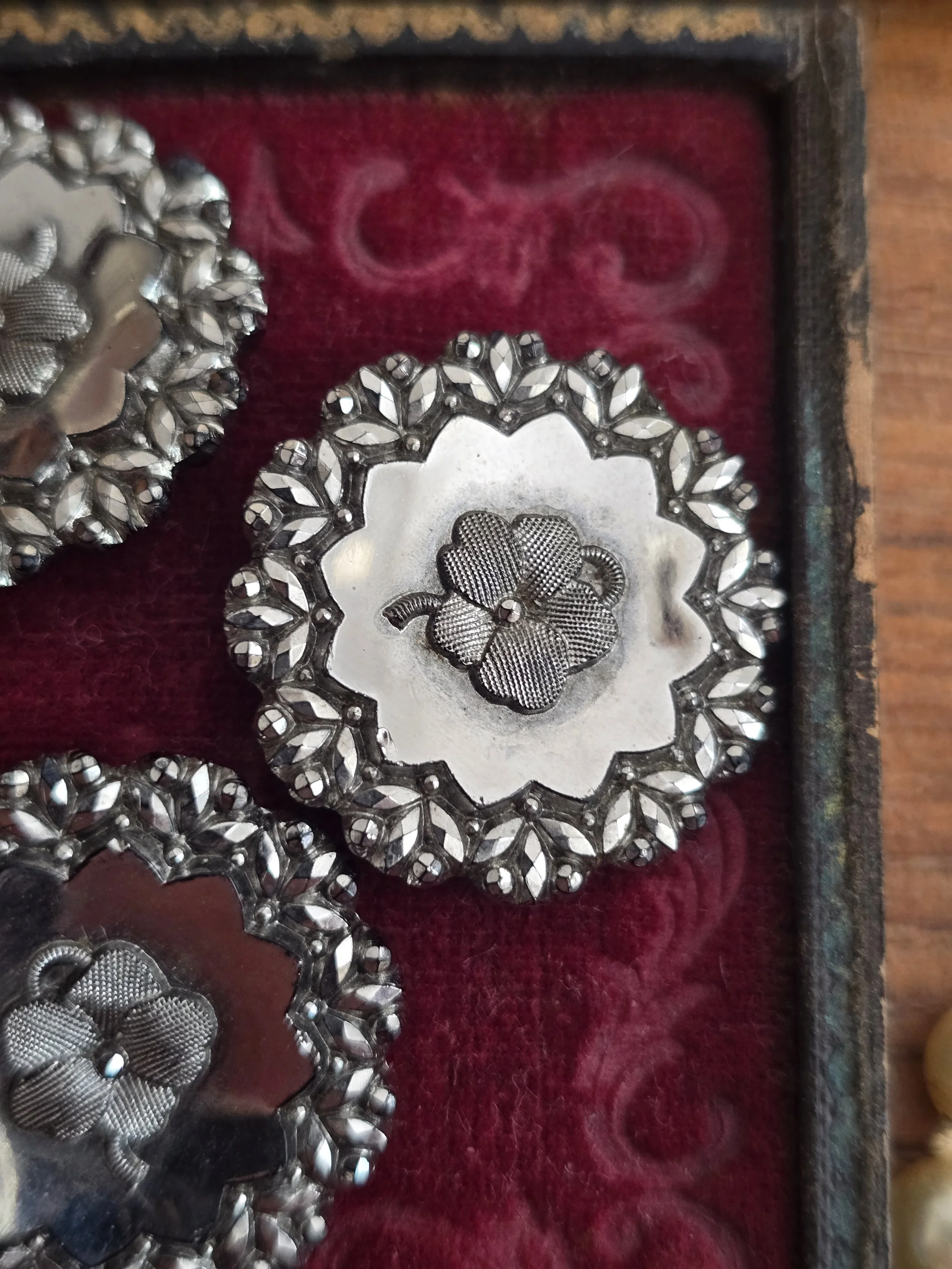 Close-up of an antique Victorian pressed steel button with engraved shamrock motif and faceted steel border.