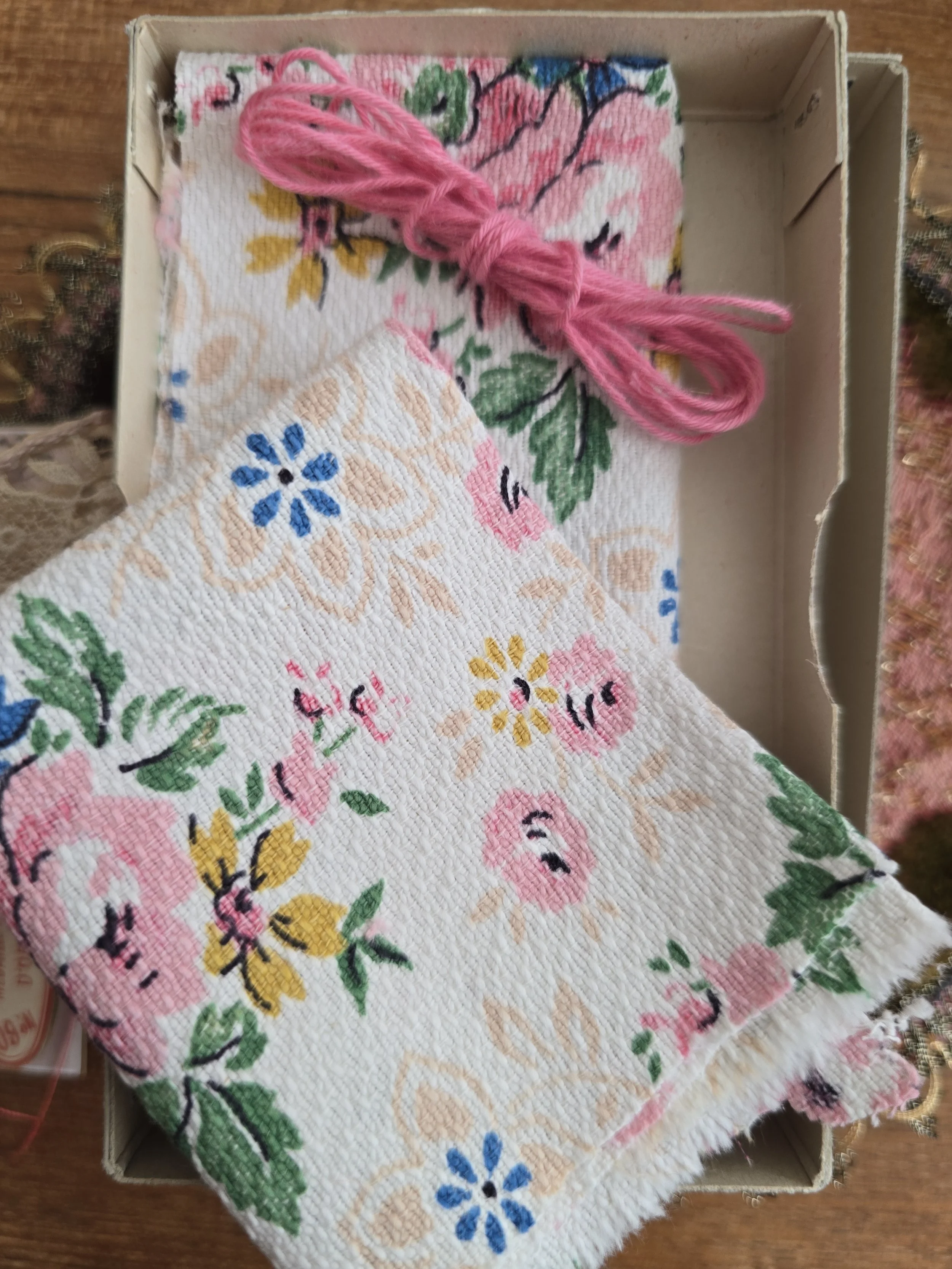 Two 1950s floral cotton fabric pieces with pink embroidery thread presented inside a vintage French À La Croix sewing box.