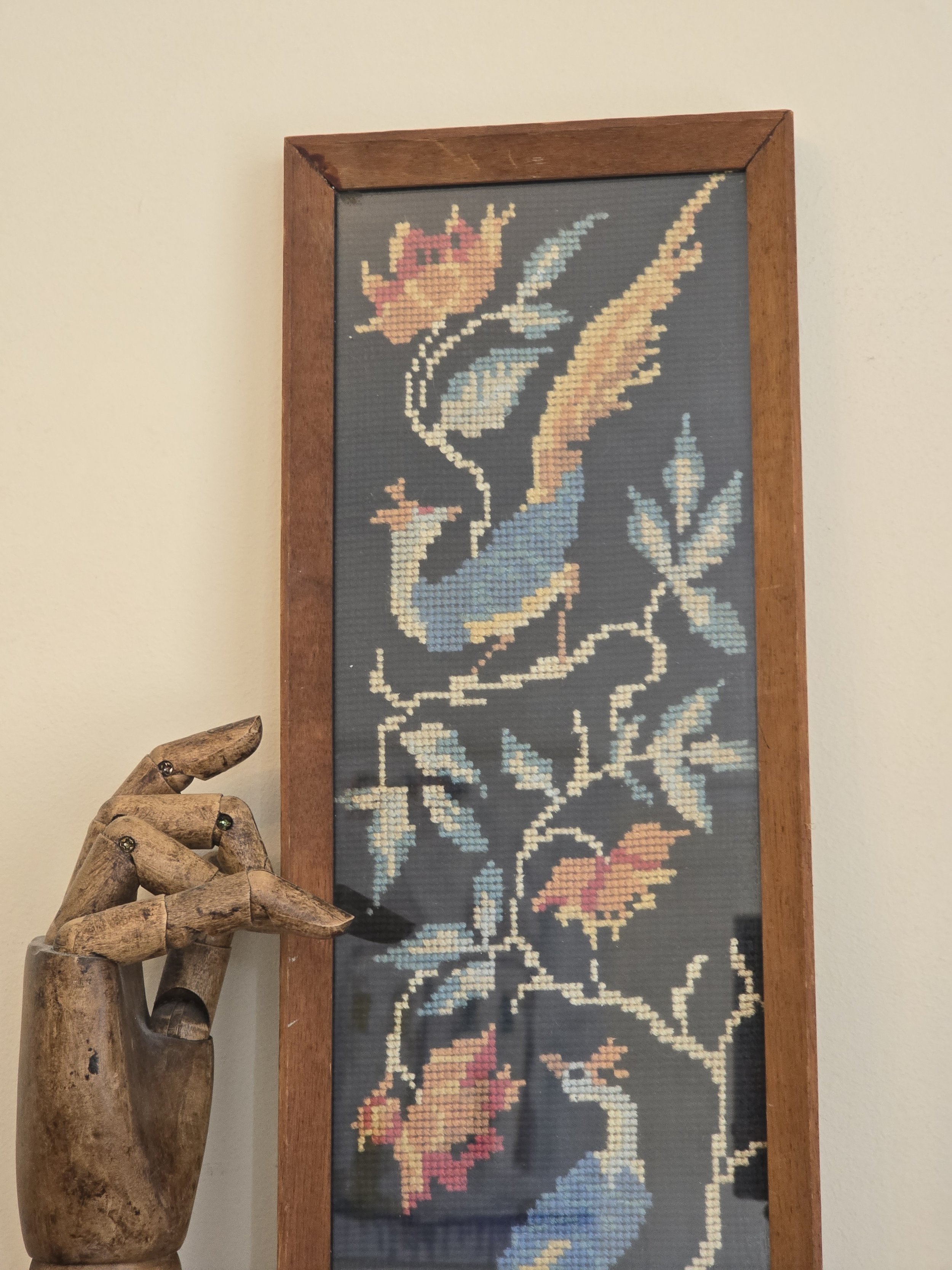 Detail of vintage folk style needlework with blue peacock and faded flowers