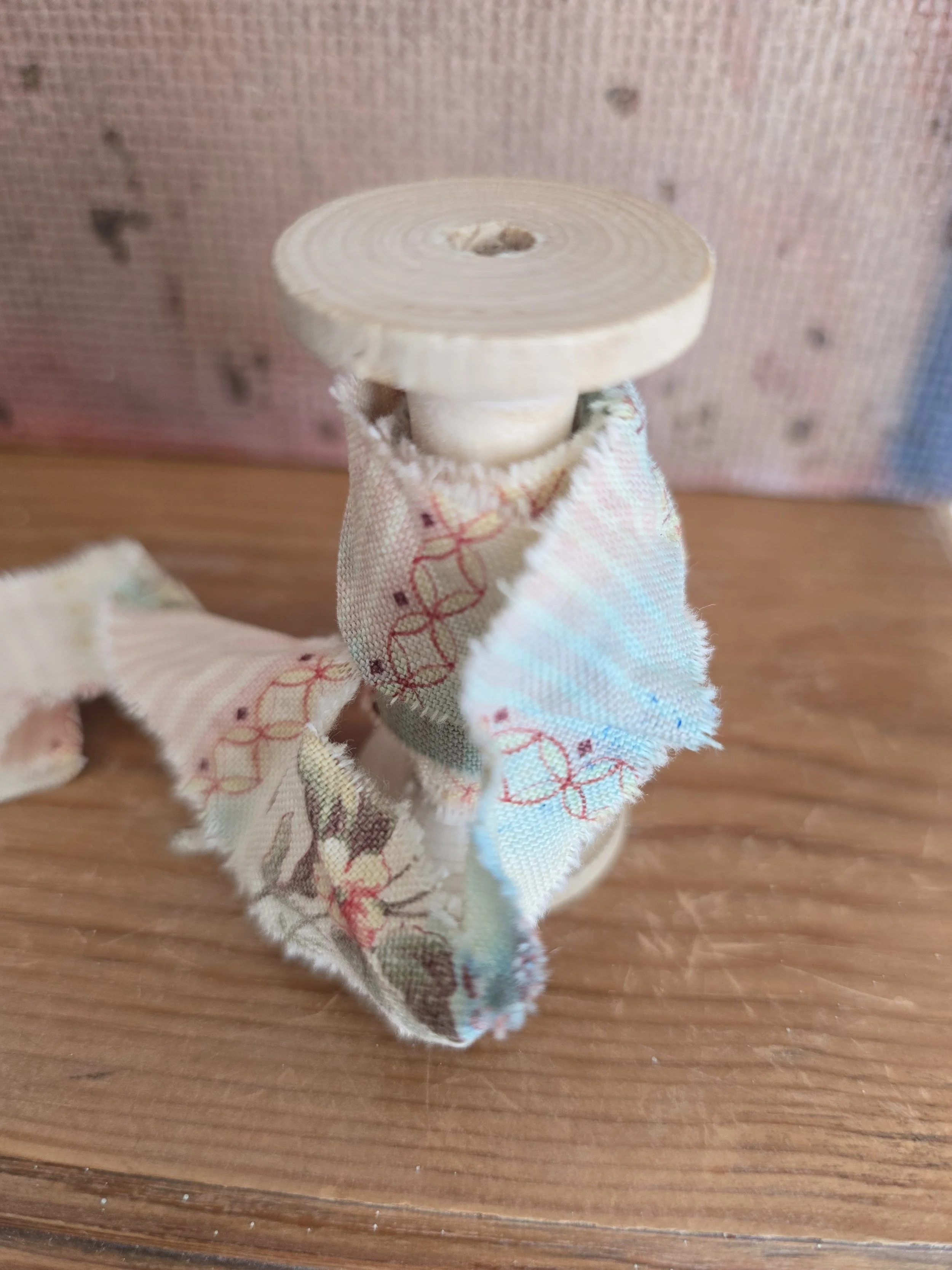 Decorative vintage ribbon displayed on an unfinished wooden spool.