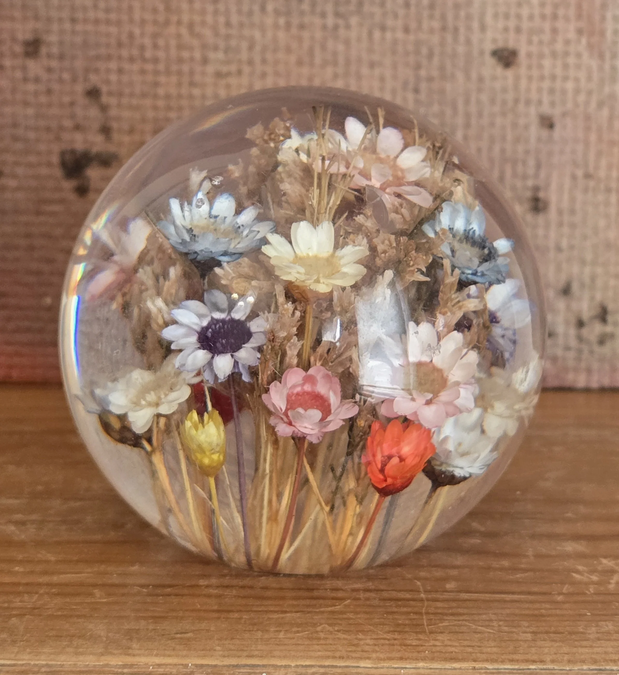 Vintage clear acrylic paperweight containing colourful dried flowers preserved inside.