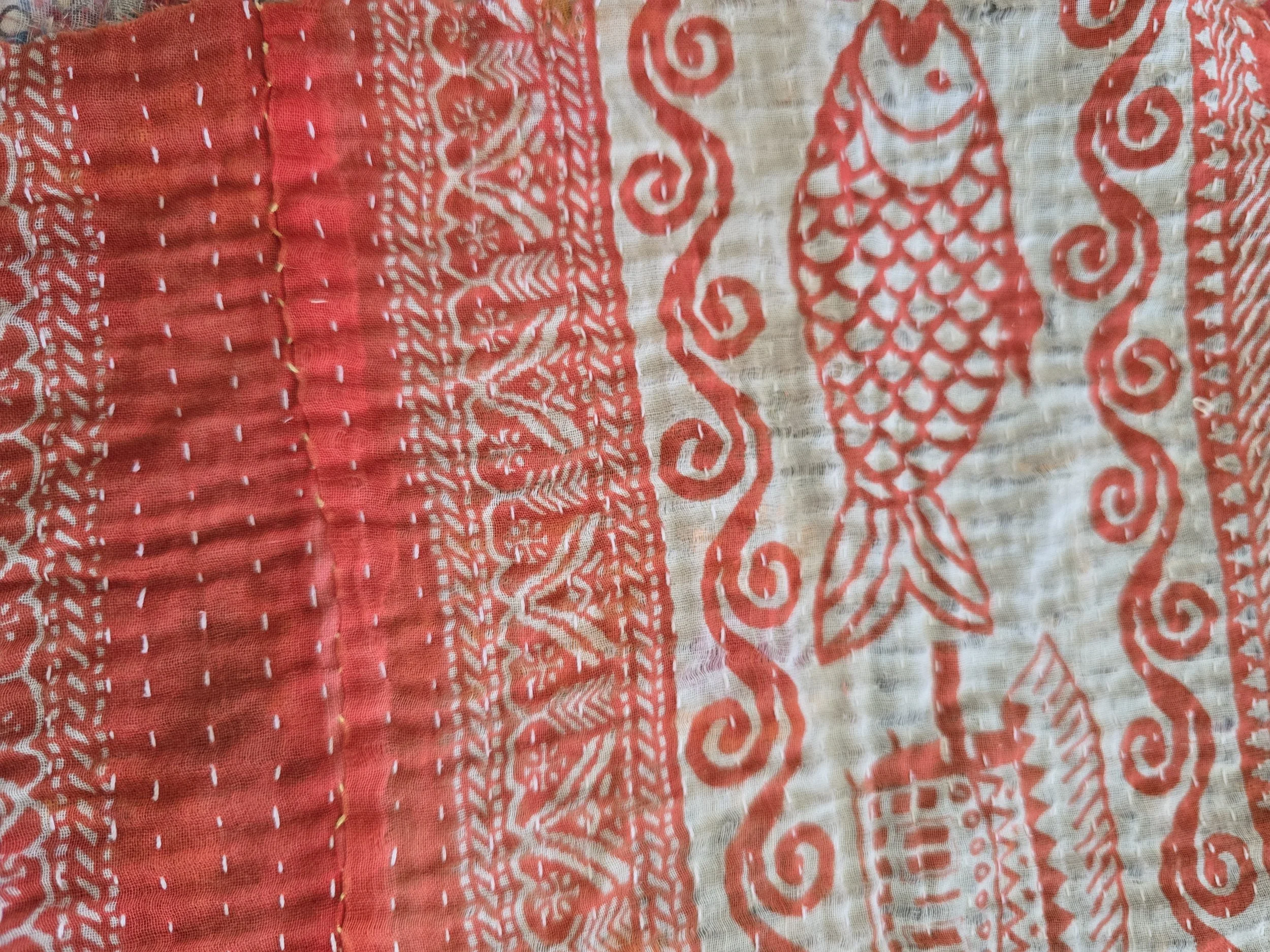 Vintage Indian kantha cloth with coral red patterns, running stitch quilting and exposed fabric layers.