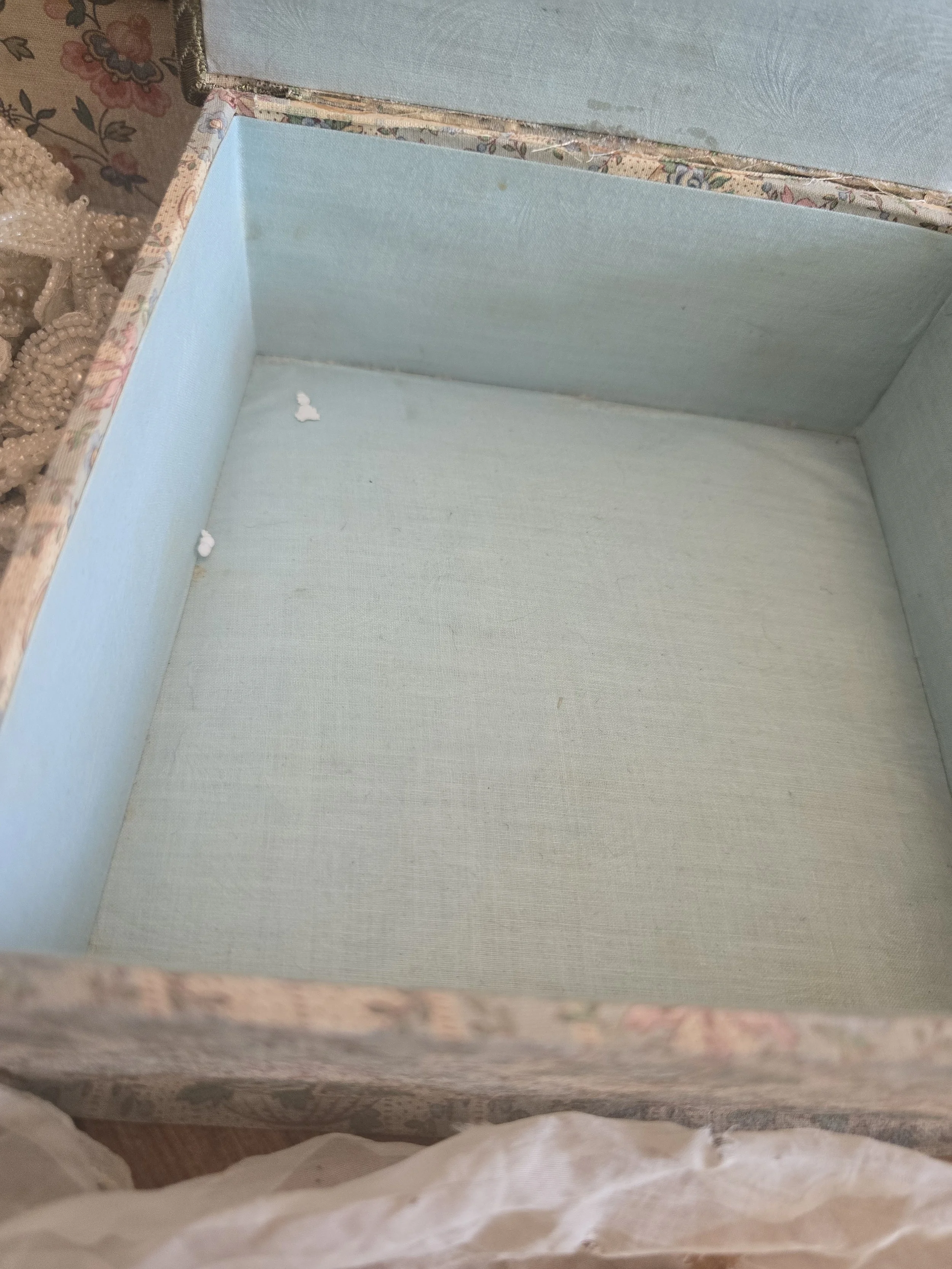 Original pale blue fabric-lined interior of antique French boudoir box showing age-related marks and wear.