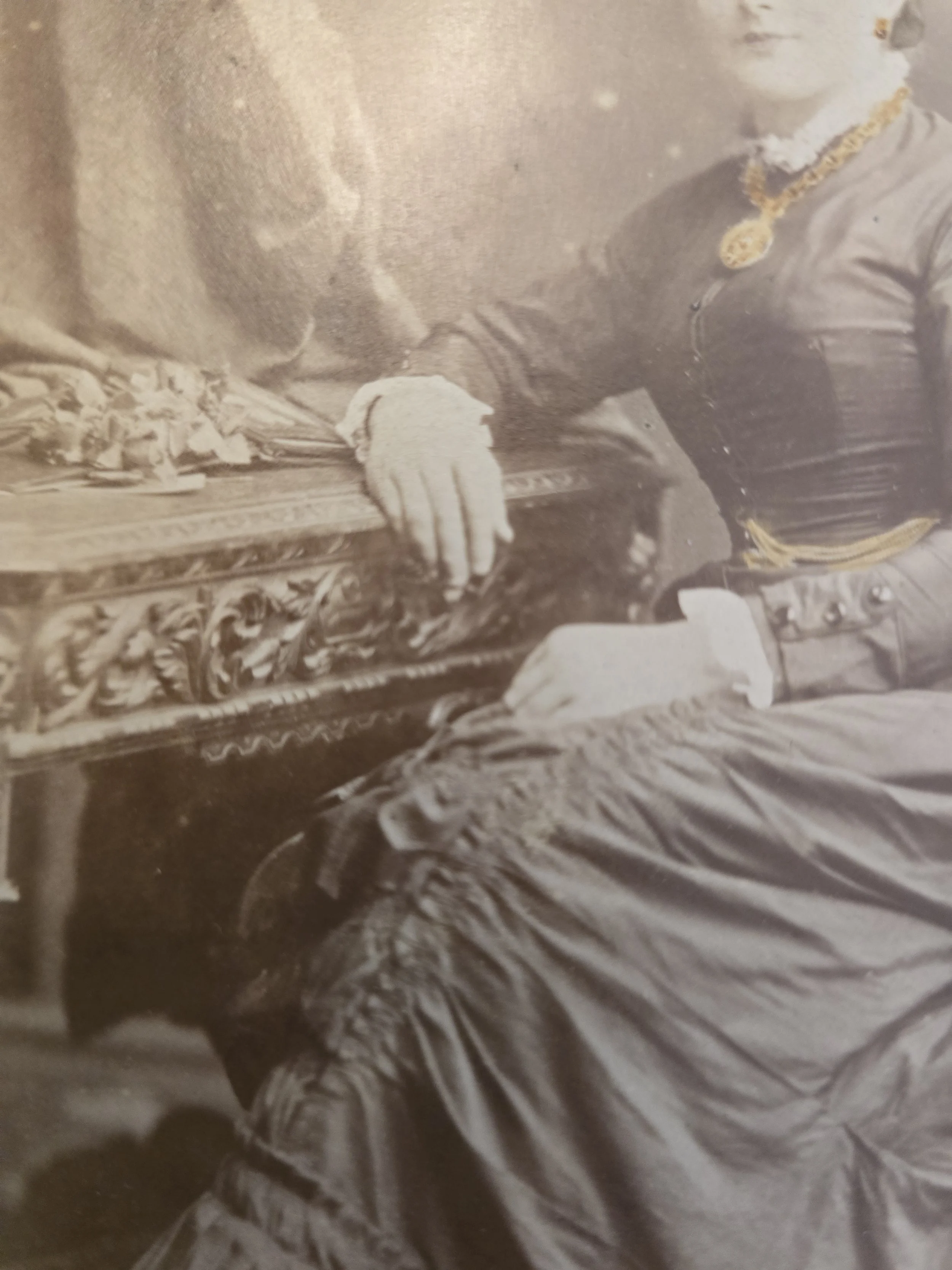 Victorian lady wearing jewellery and formal dress in a studio setting.