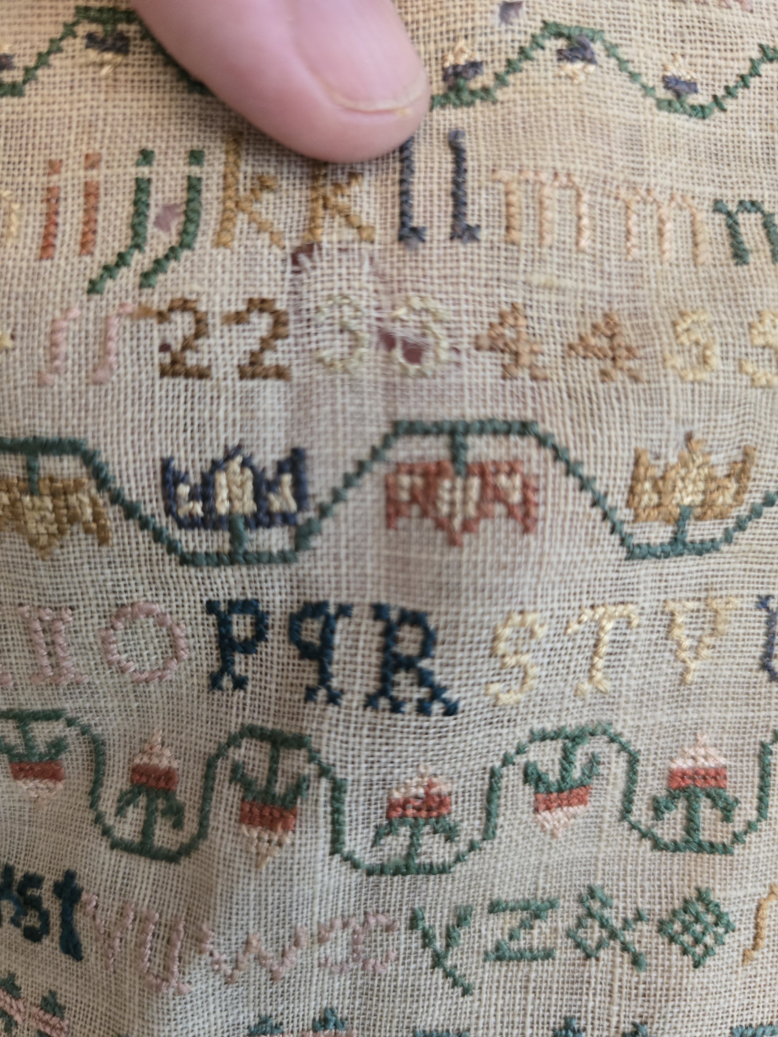 Detail of hand embroidered verse stitched in faded pink silk on antique linen ground.