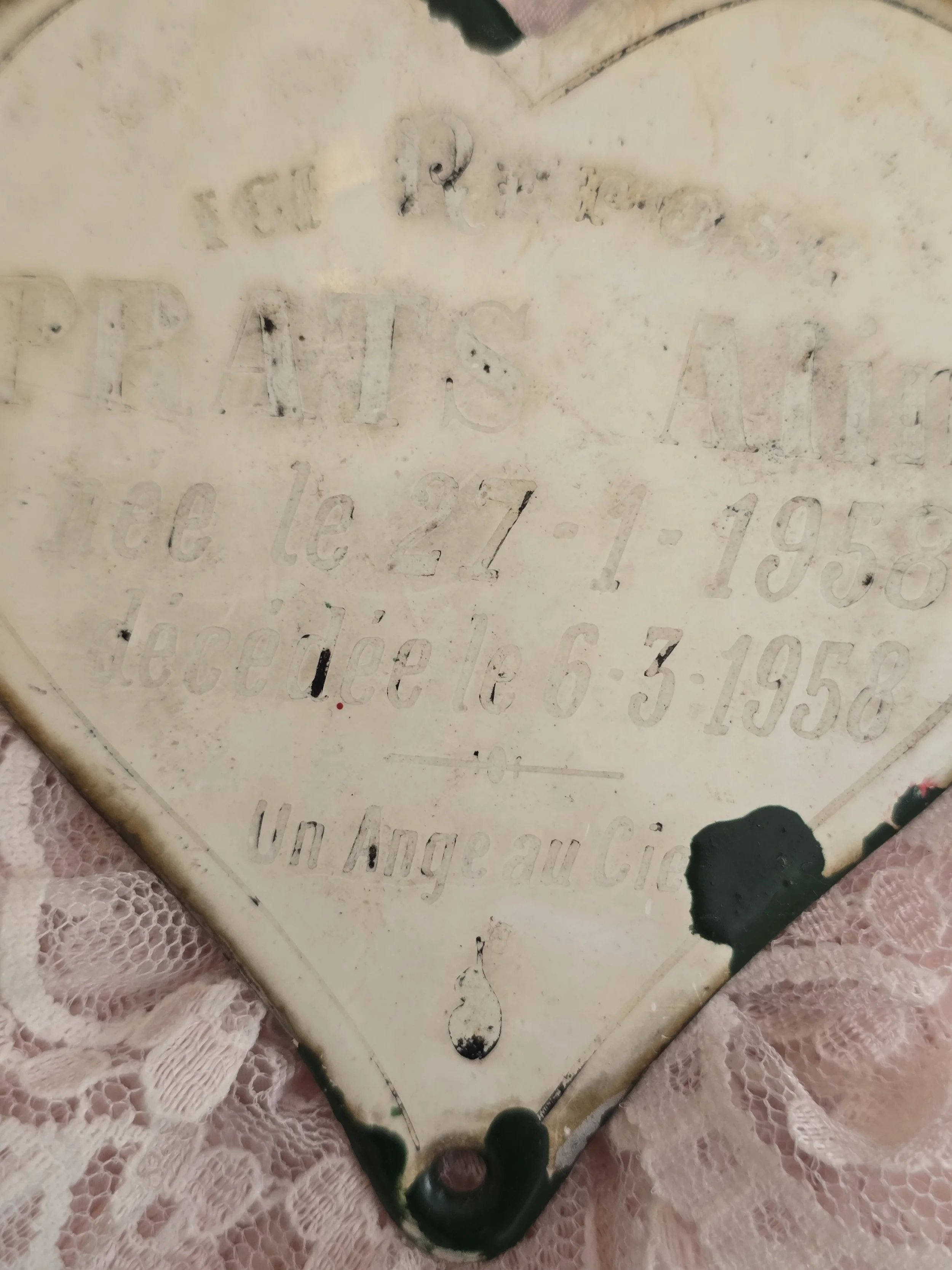 Faded inscription on vintage French cemetery memorial heart