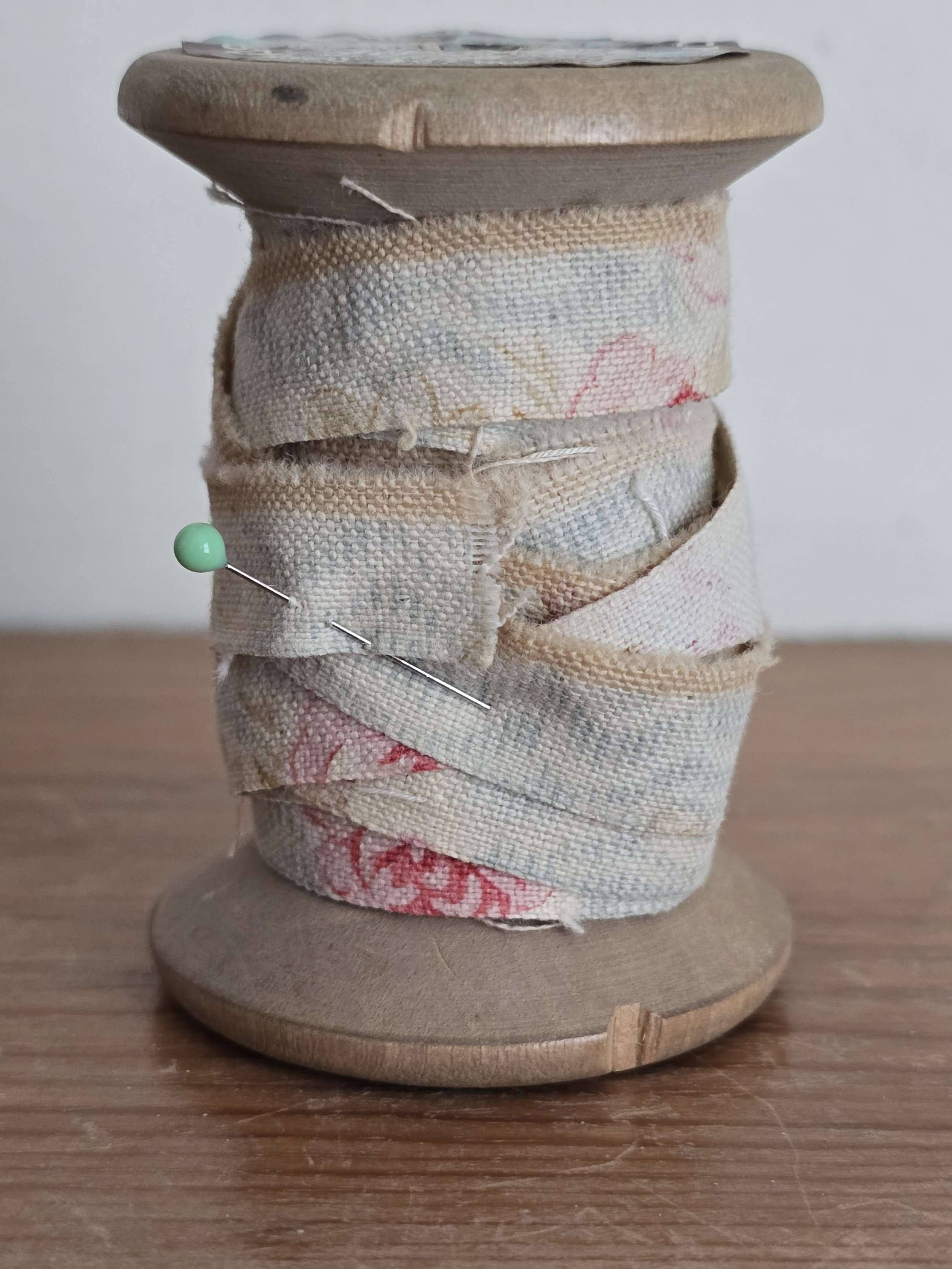 antique floral fabric strip on vintage wooden spool, side view