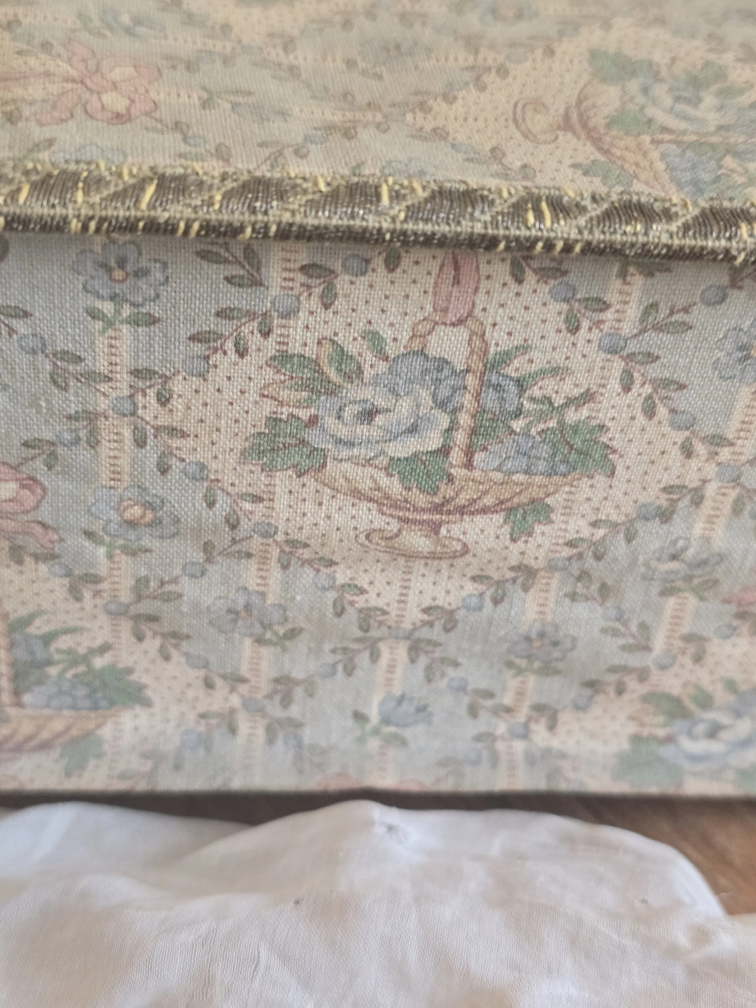 Side of antique French boudoir box showing original rose basket fabric and aged metallic edging.
