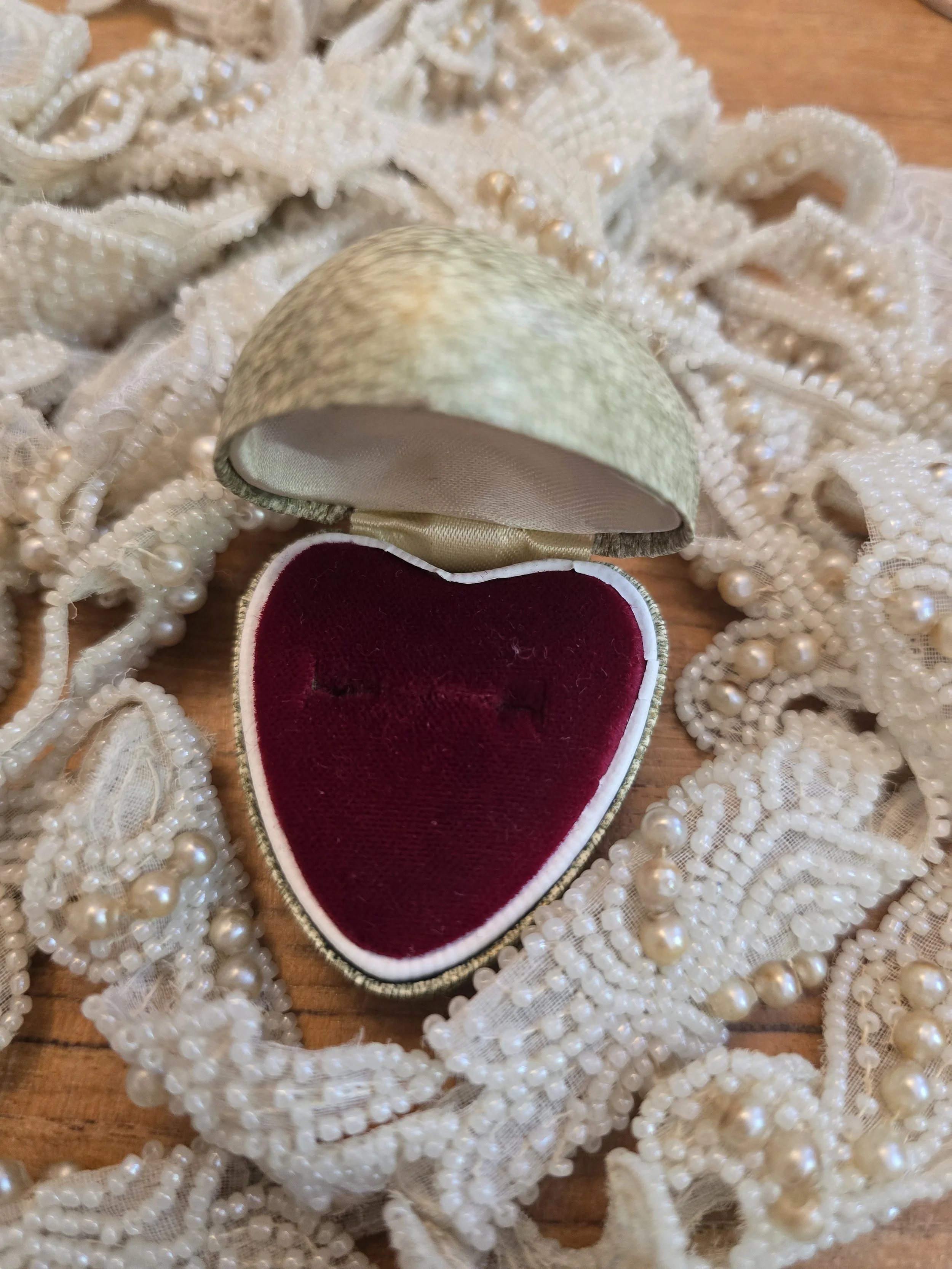 Open heart shaped jewellery box with rich ruby red velvet interior and cream trim.