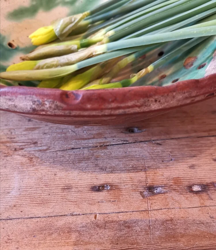 Side view of antique fruit drainer bowl with hand-drilled holes and vibrant glaze, displayed with vintage flowers