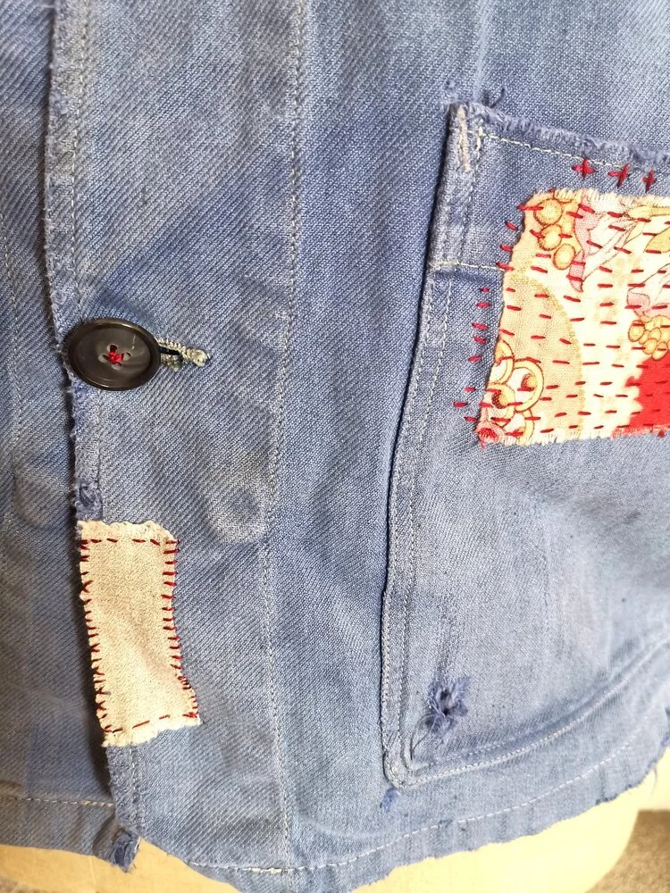 Layered visible mending on faded blue cotton