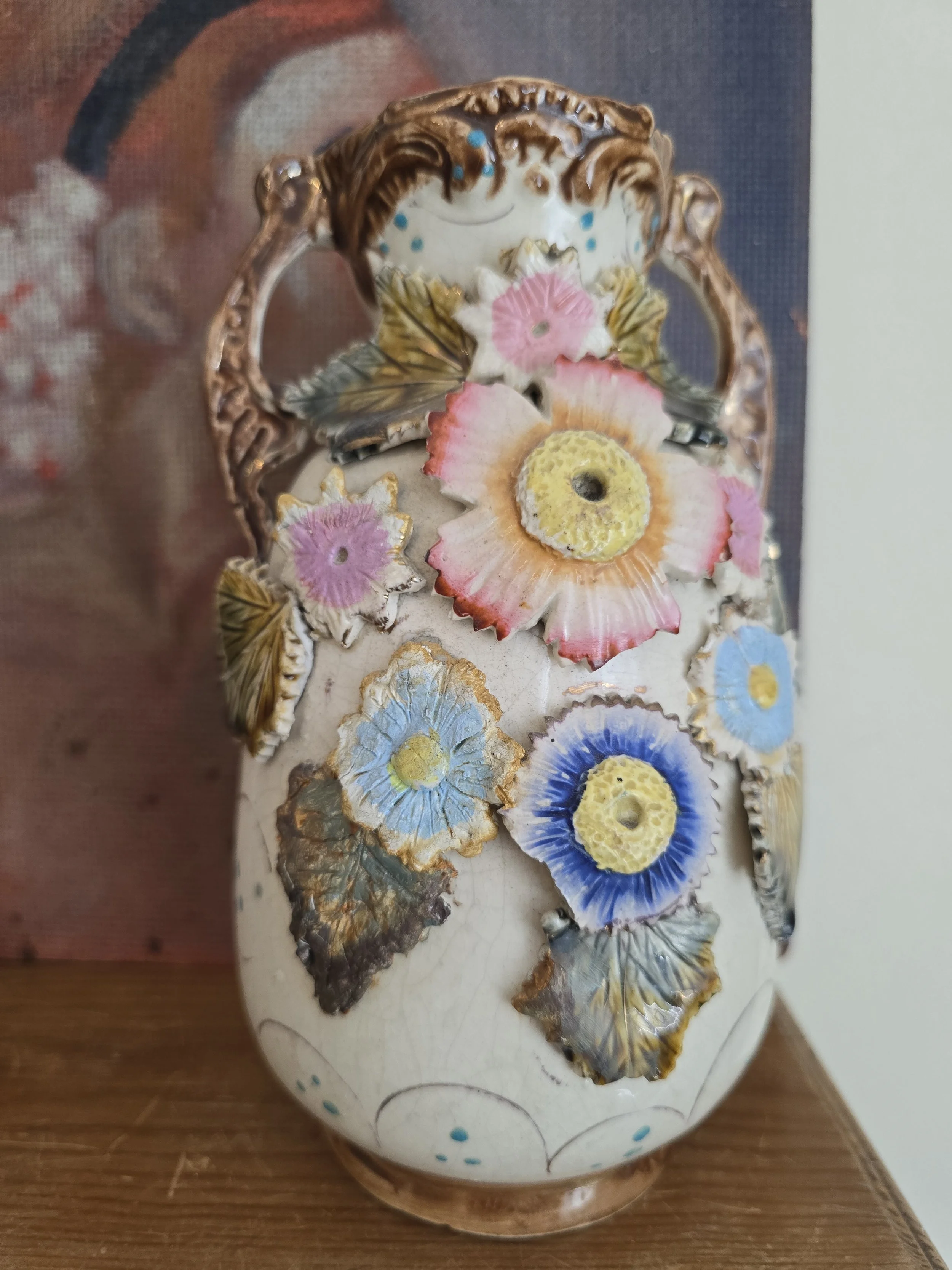 Majolica style vase featuring raised pink, blue and cream flowers
