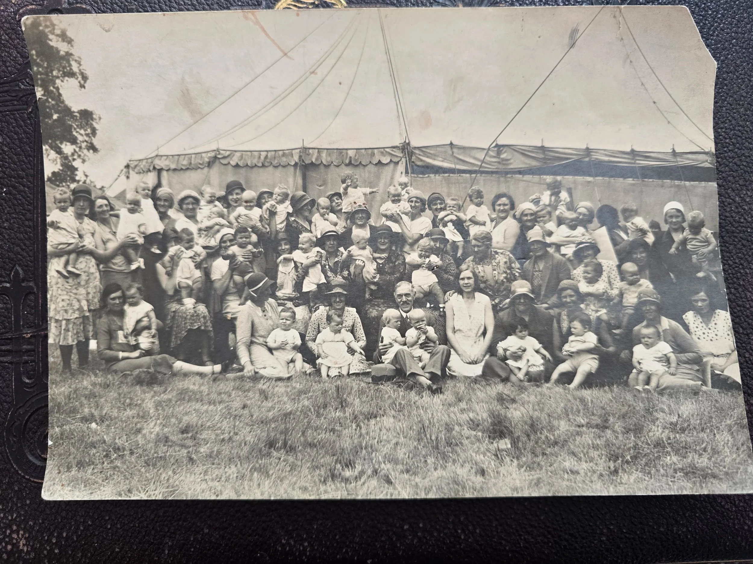 Original 1930s group photograph of women, babies and children gathered beside a large canvas big top tent.