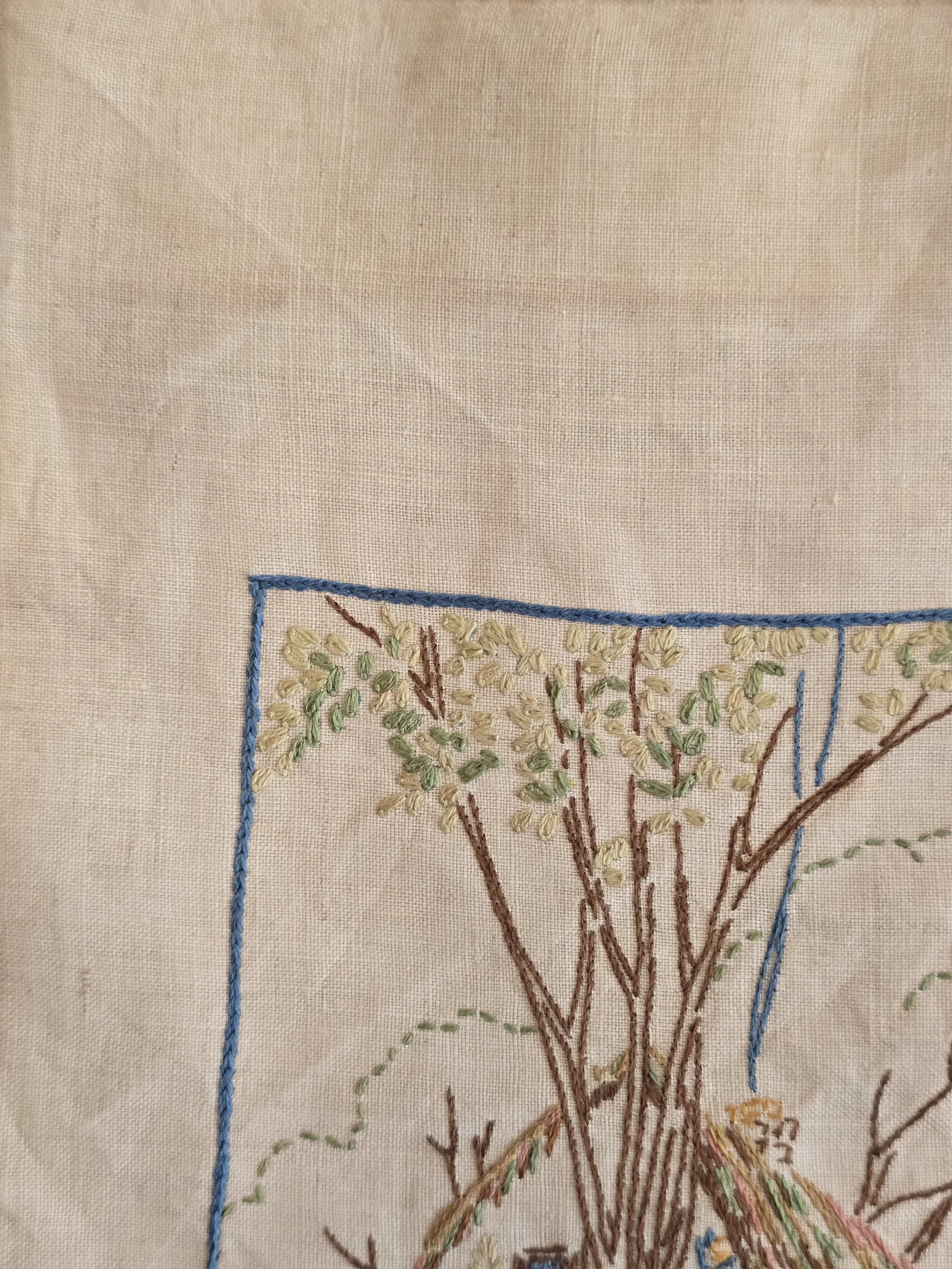 Vintage textile panel featuring pastel floral embroidery and countryside cottage.