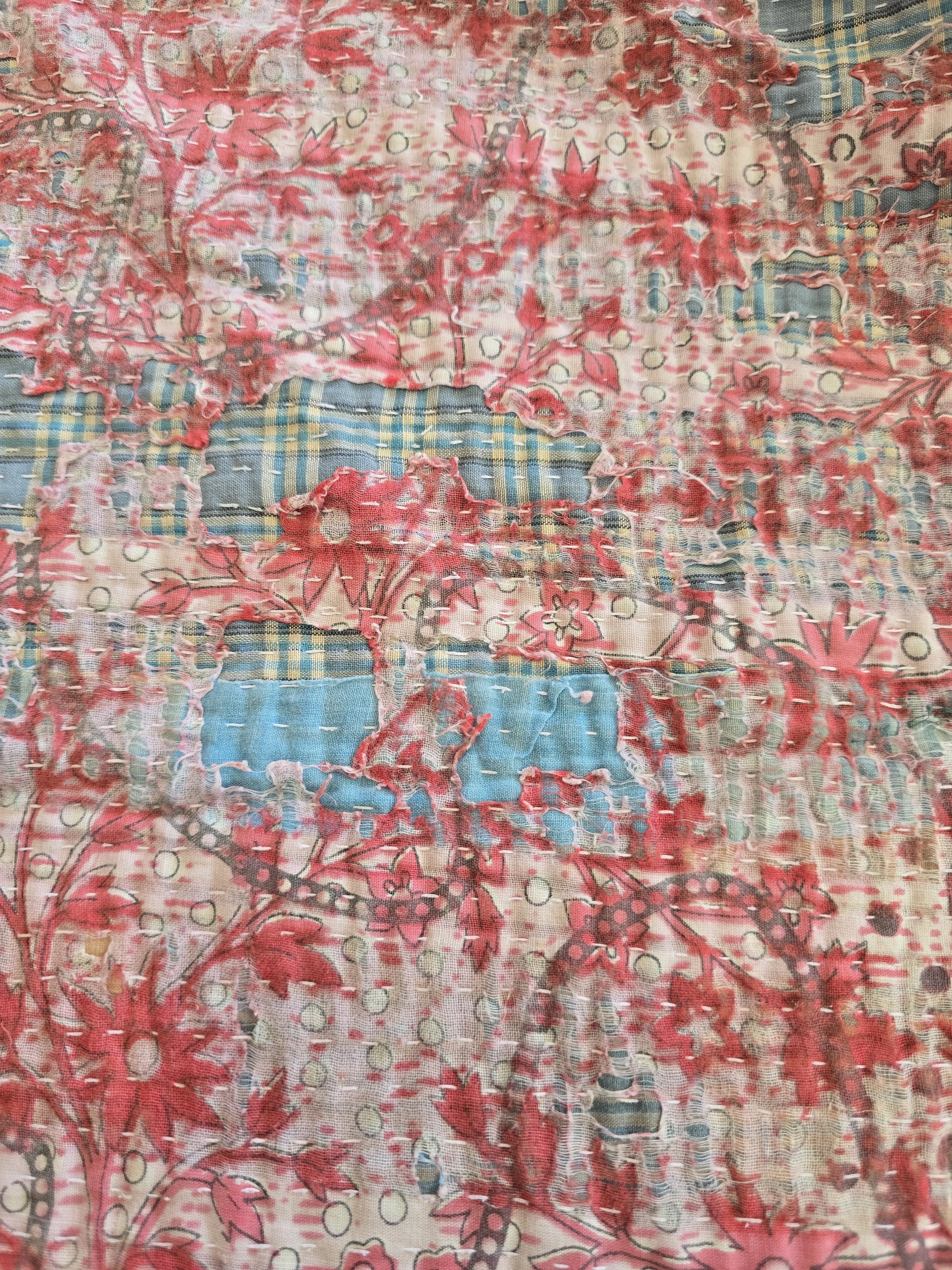 Timeworn kantha cloth showing exposed fabric layers, running stitches and decorative printed cotton.