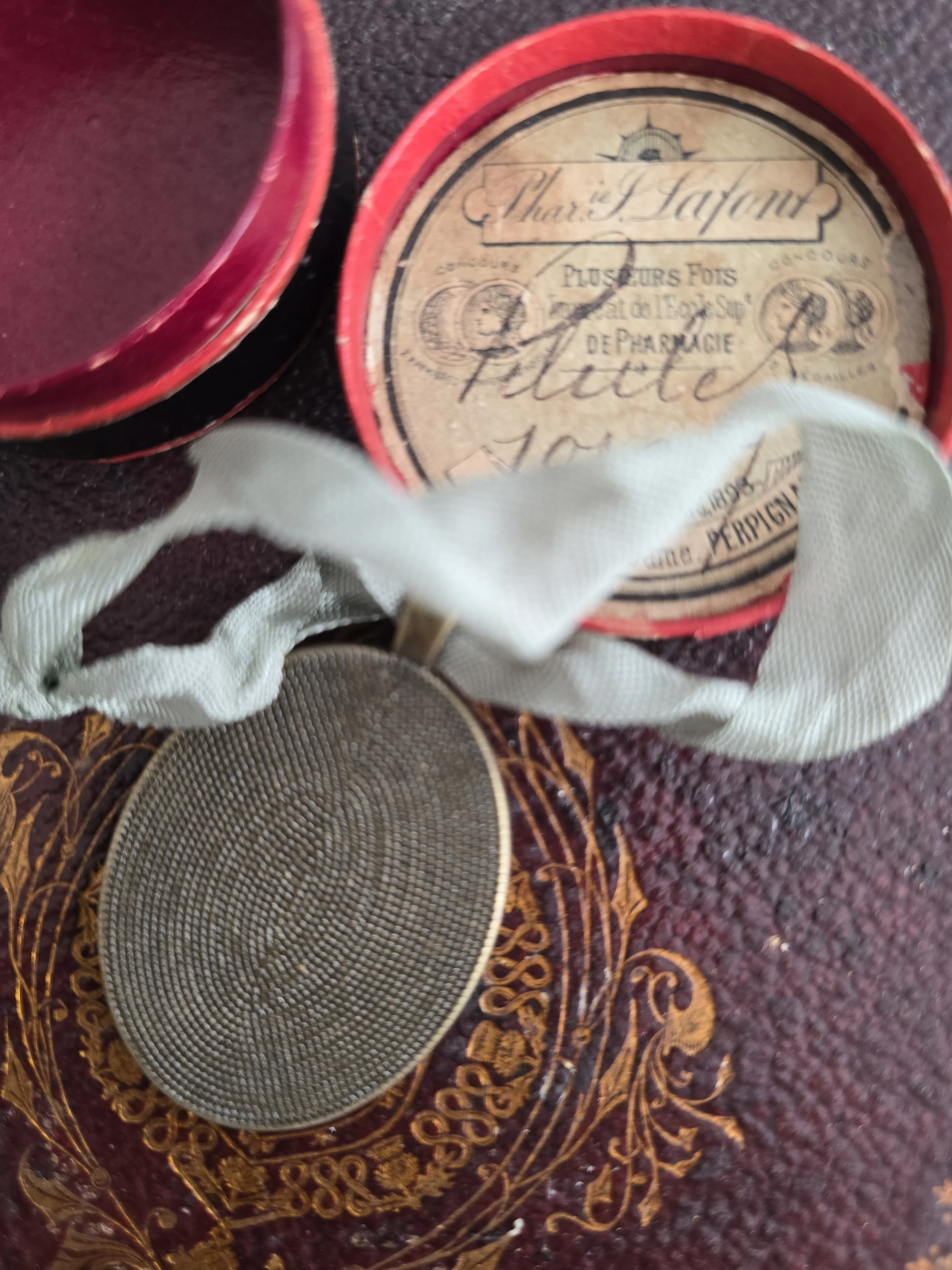 Reverse of the oval pendant showing textured brass-tone finish.