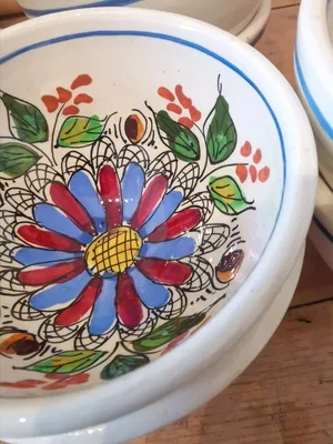 Close-up of hand painted folk-art floral design inside vintage French bowl with red, blue, and green decoration.