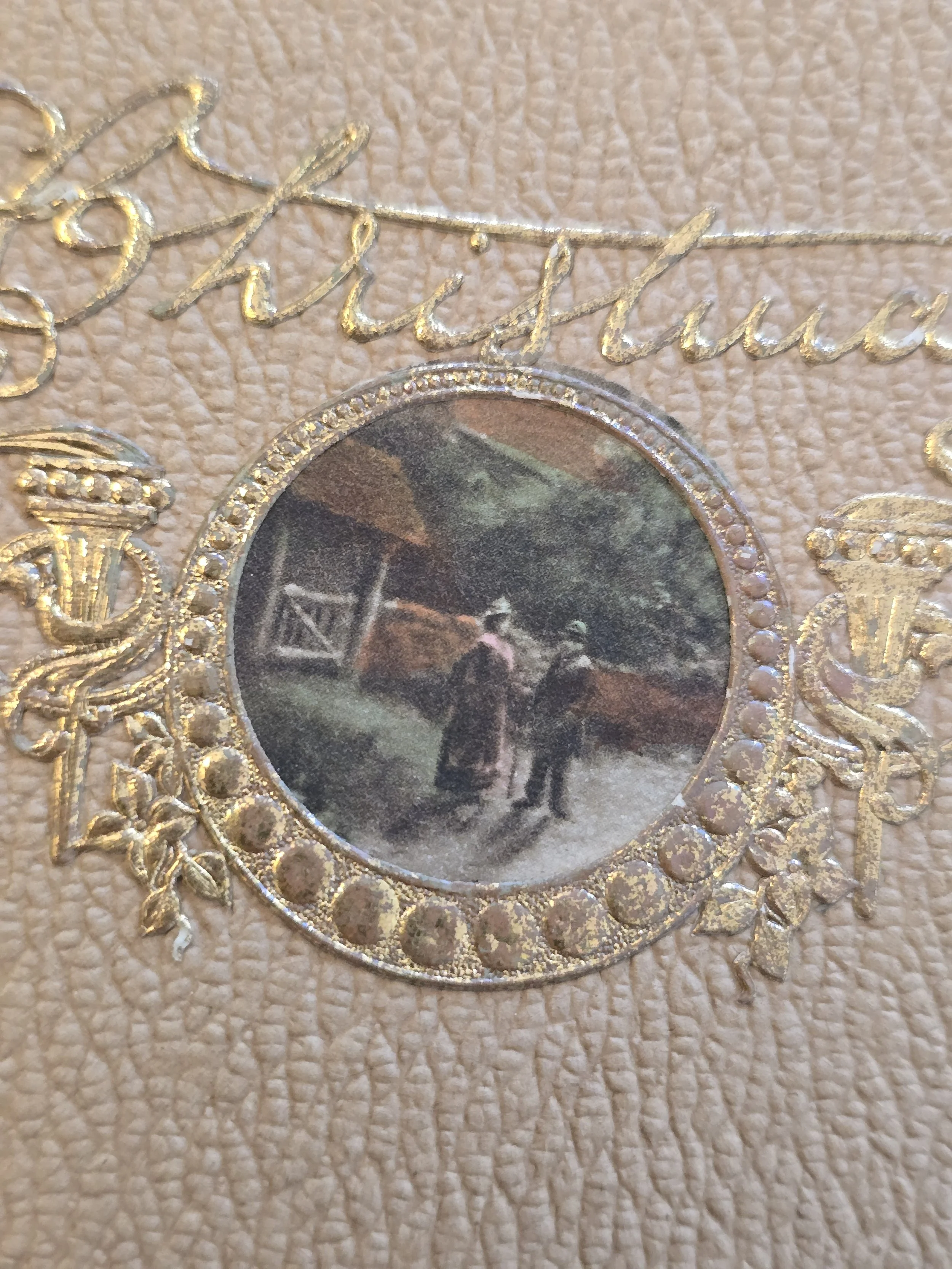 Close-up of miniature pastoral scene and worn gold decoration on antique French Christmas card.