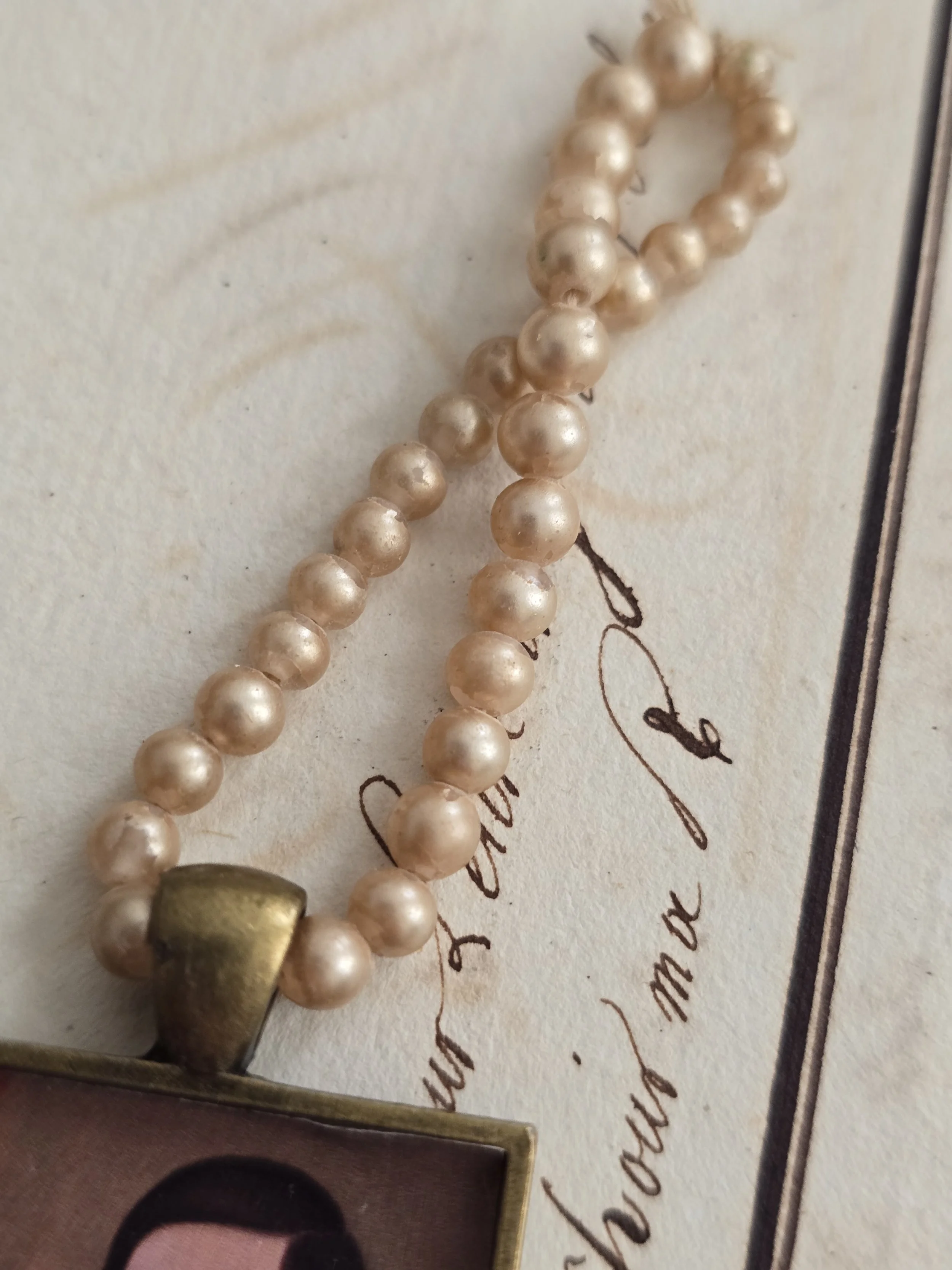 Decorative portrait keepsake with antiqued brass setting and vintage pearls.