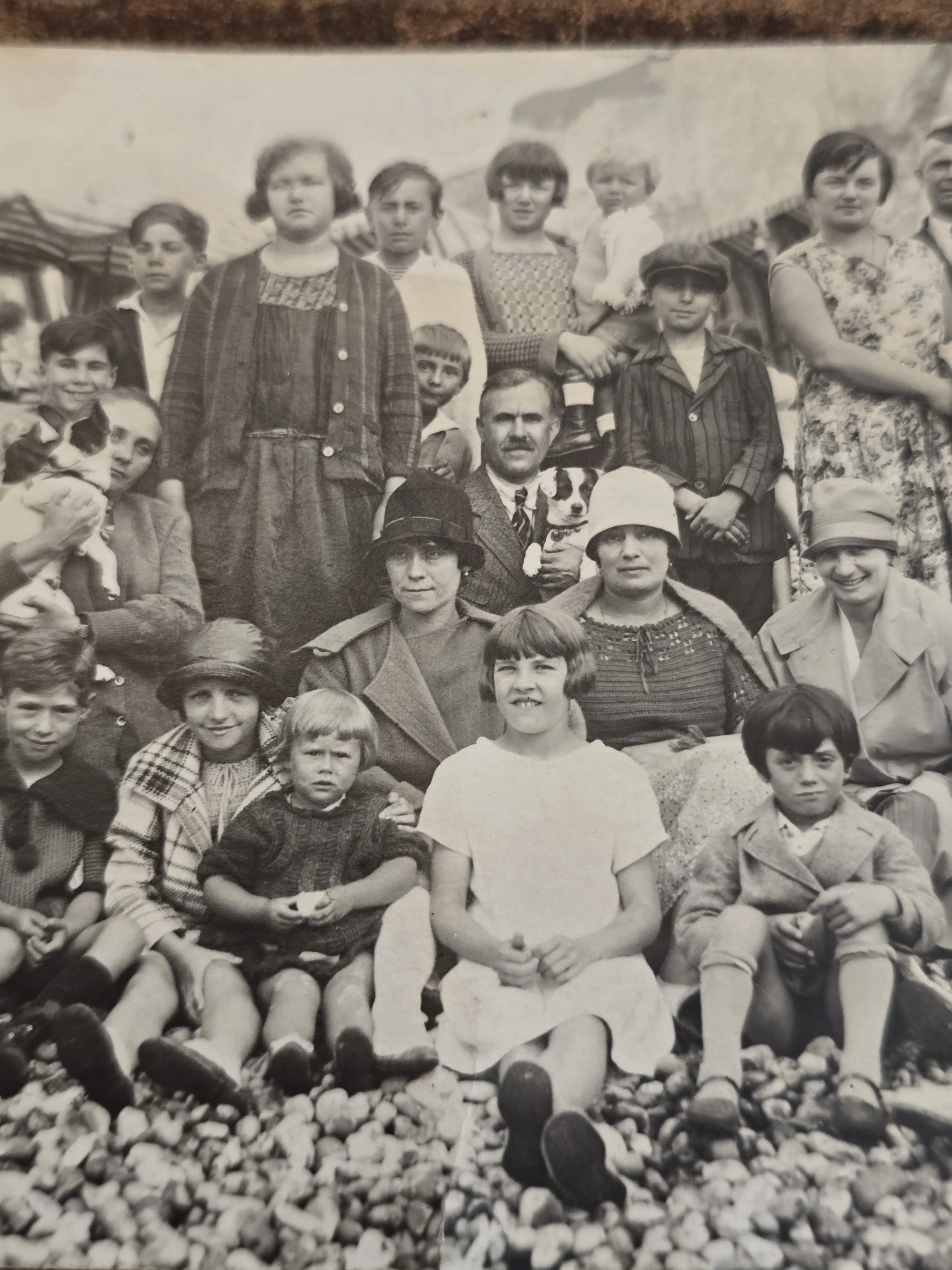Detail of children seated on pebbles in an early twentieth century beach photograph.