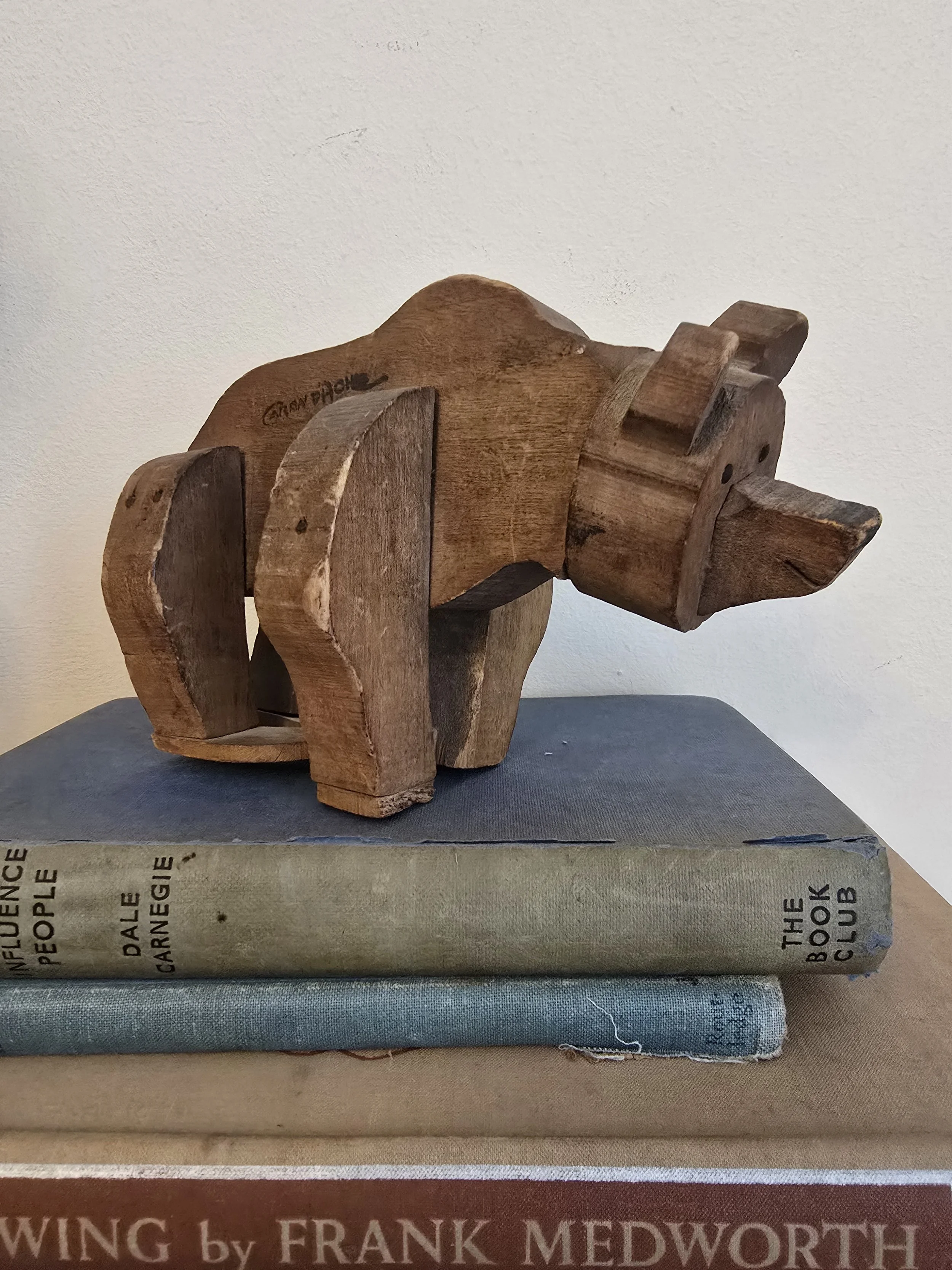 Full view of the wooden bear toy standing on vintage books showing charming folk-style craftsmanship