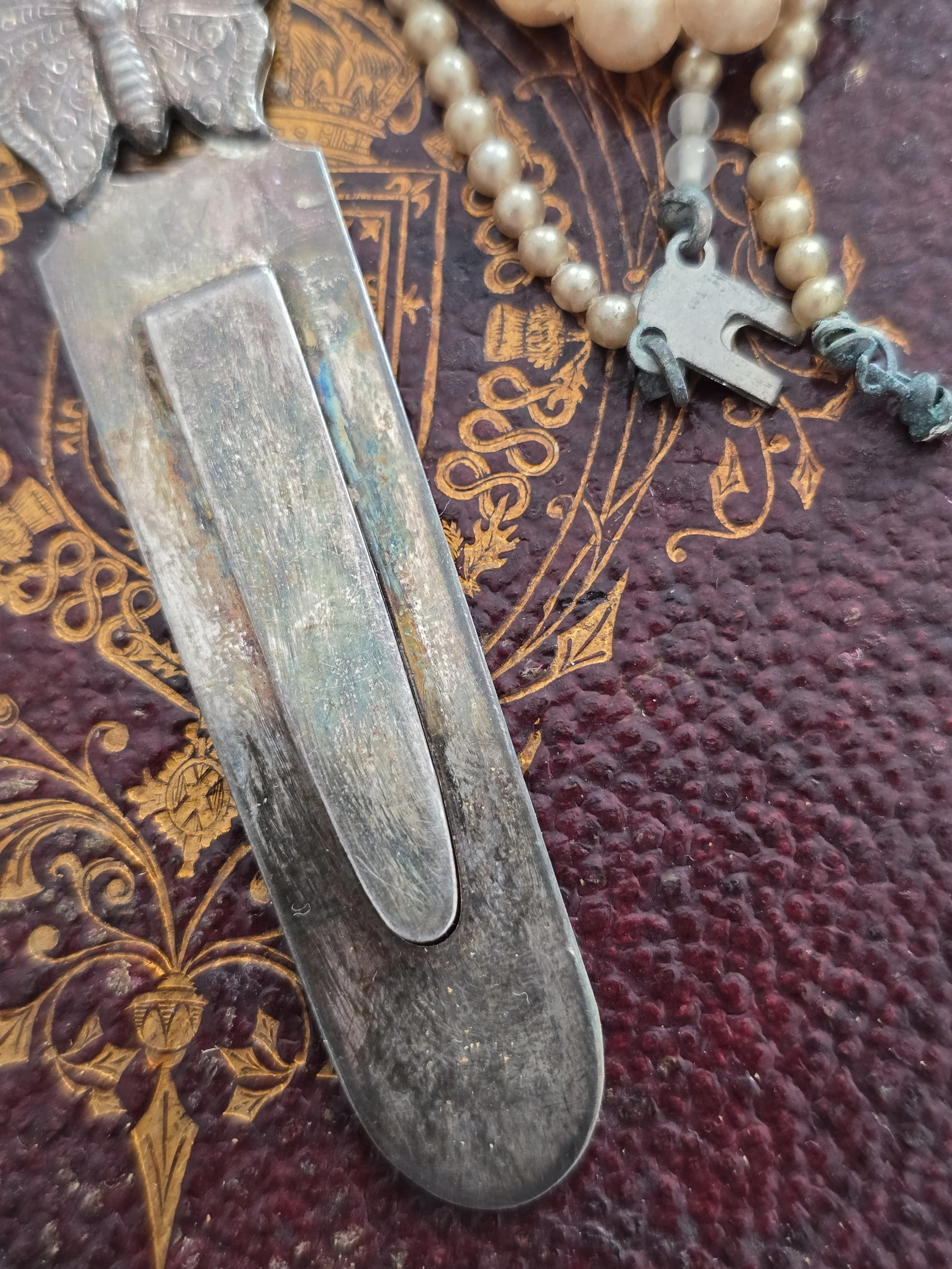 Close-up of embossed butterfly detail on vintage silver bookmark.