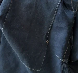 Sleeve and underarm seam detail with small hole visible.