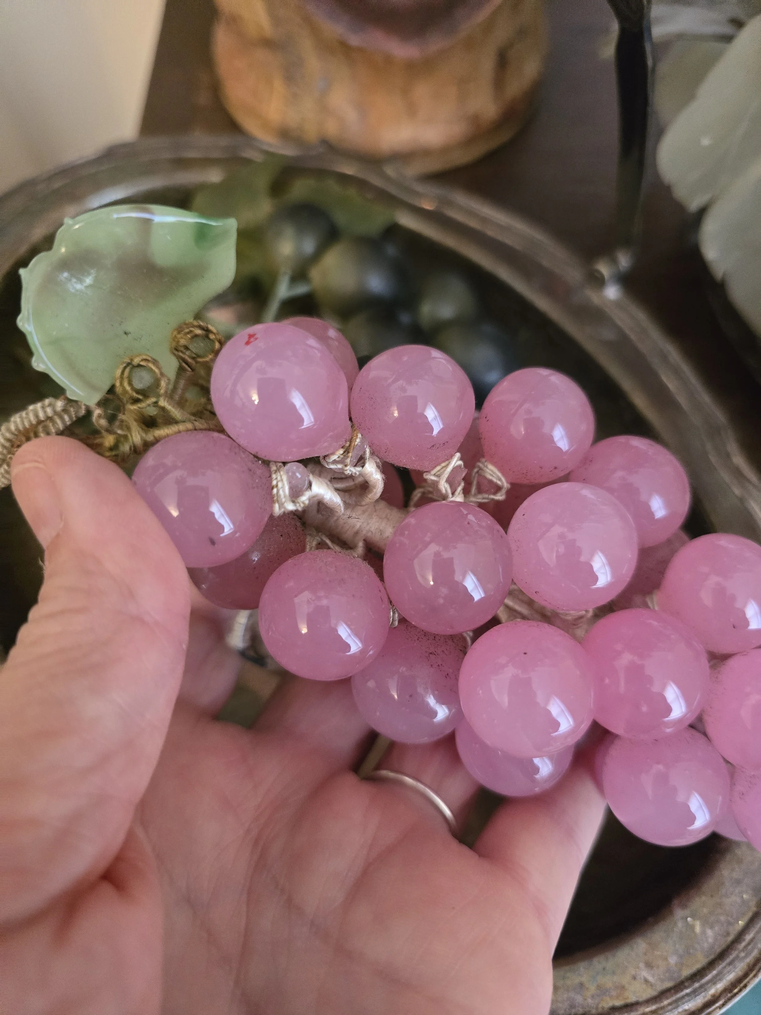 Close-up of vintage pink glass grapes showing individual rounded translucent glass fruits and wrapped stems.